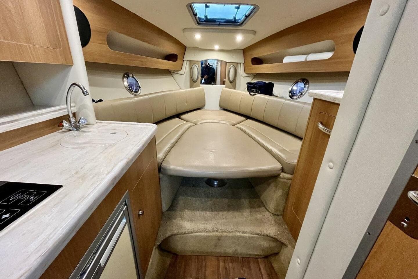 2014 Rinker 290 Express Cruiser interior with beige seating and compact kitchenette.