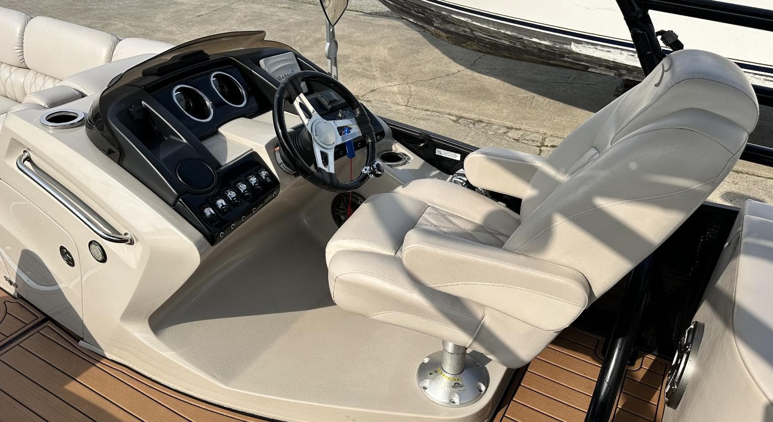 2014 Bennington 2550 QSR boat helm with beige captain's chair and control panel.