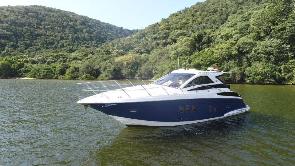 2015 Regal 42 Sport Coupe yacht on a scenic lake with lush green hills.
