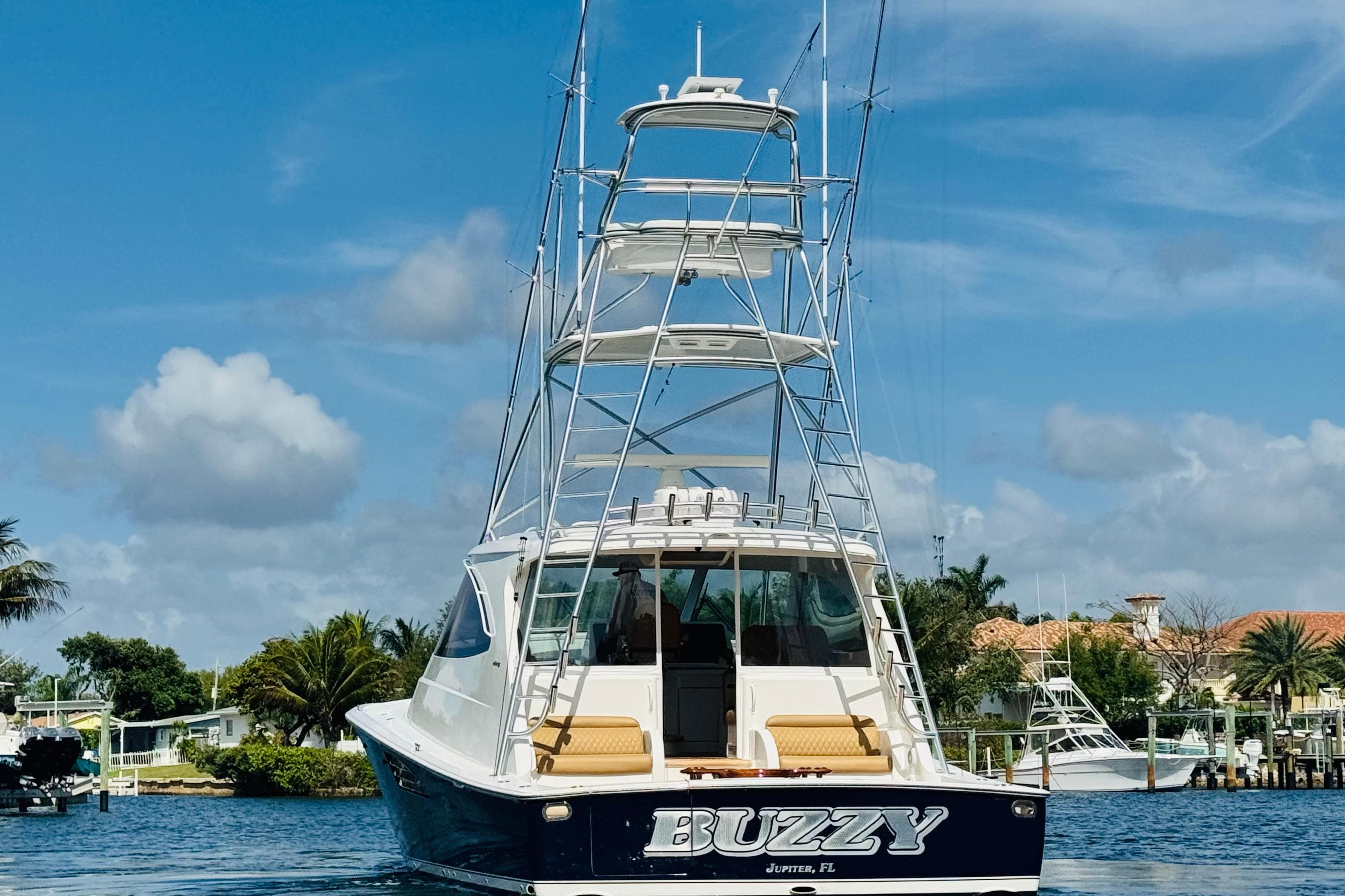 2017 Viking 52 Sport Tower yacht on water, clear sky, palm trees in background.