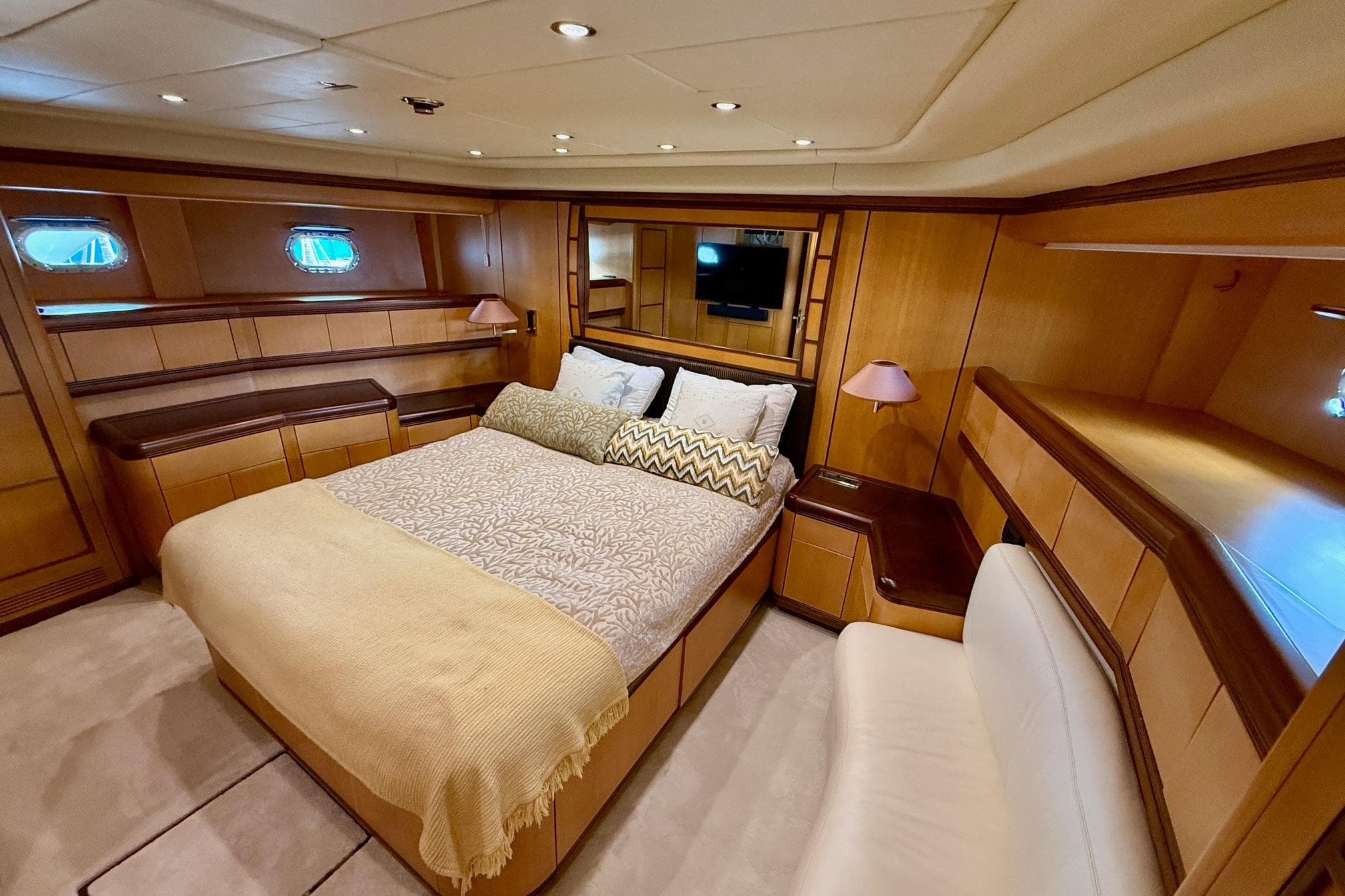 Luxurious bedroom interior of 2005 Mangusta 92 yacht with elegant wood paneling.