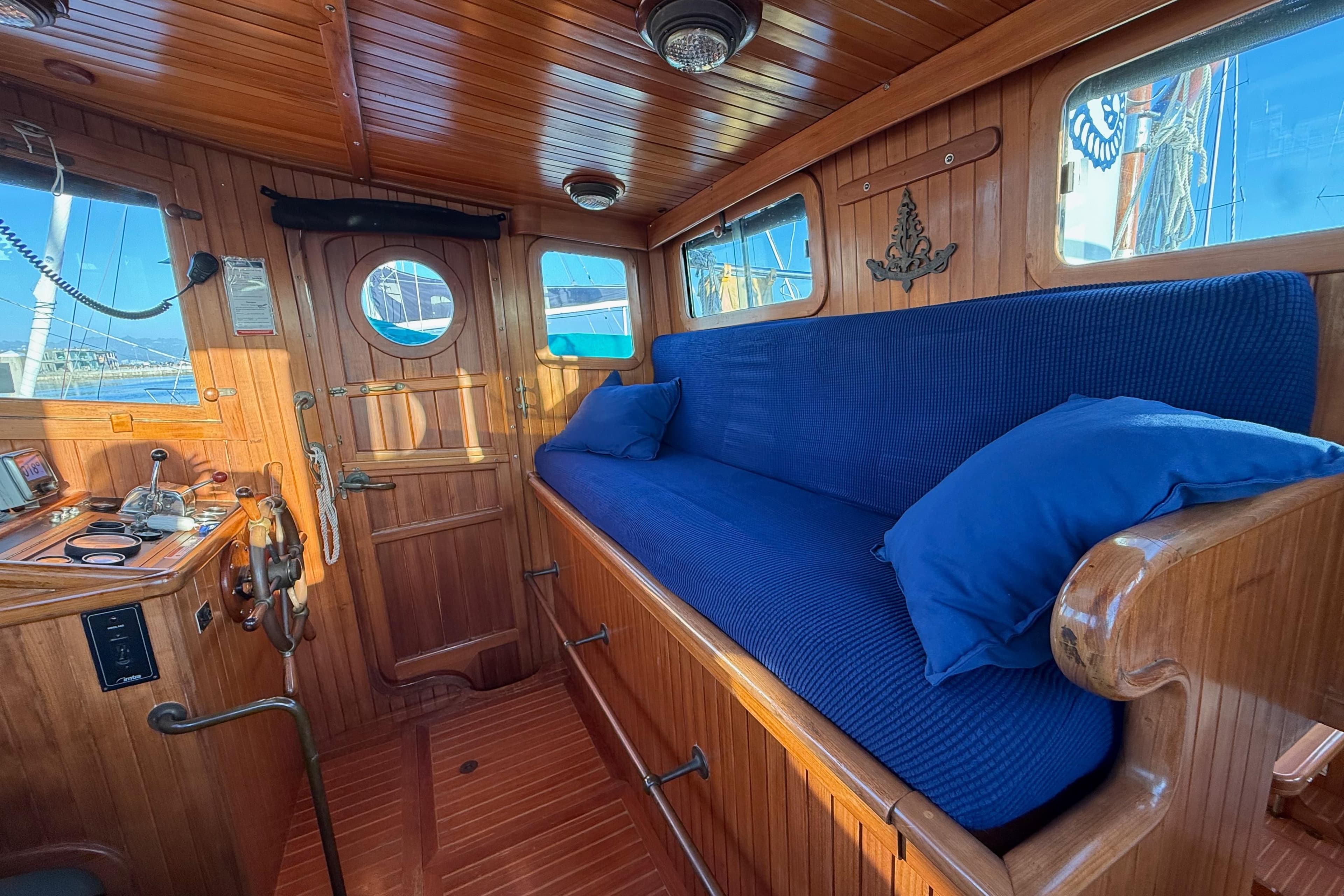 Cozy wooden interior of 1987 Lord Nelson Victory Tug with blue cushioned seating.