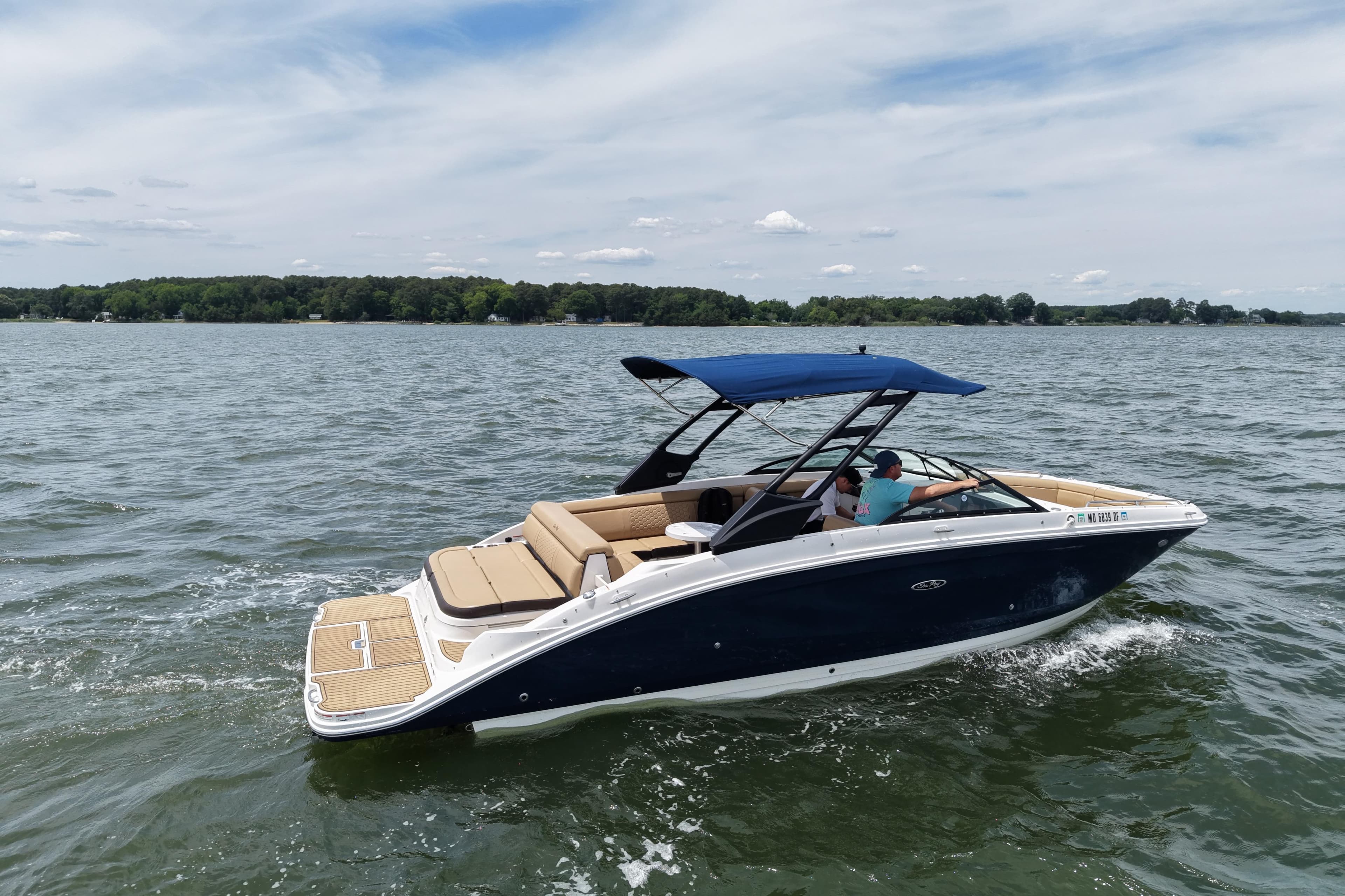 2021 Sea Ray SDX 270 boat cruising on a lake under a clear sky.