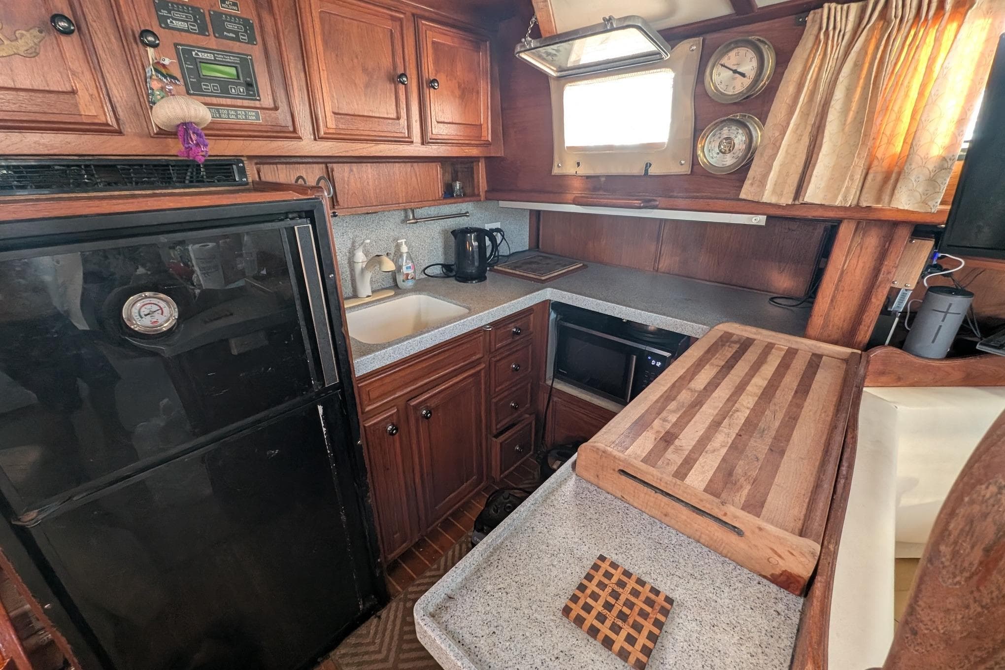 Cozy 1973 Maple Leaf 48 yacht kitchen with wooden cabinets, appliances, and cutting board.