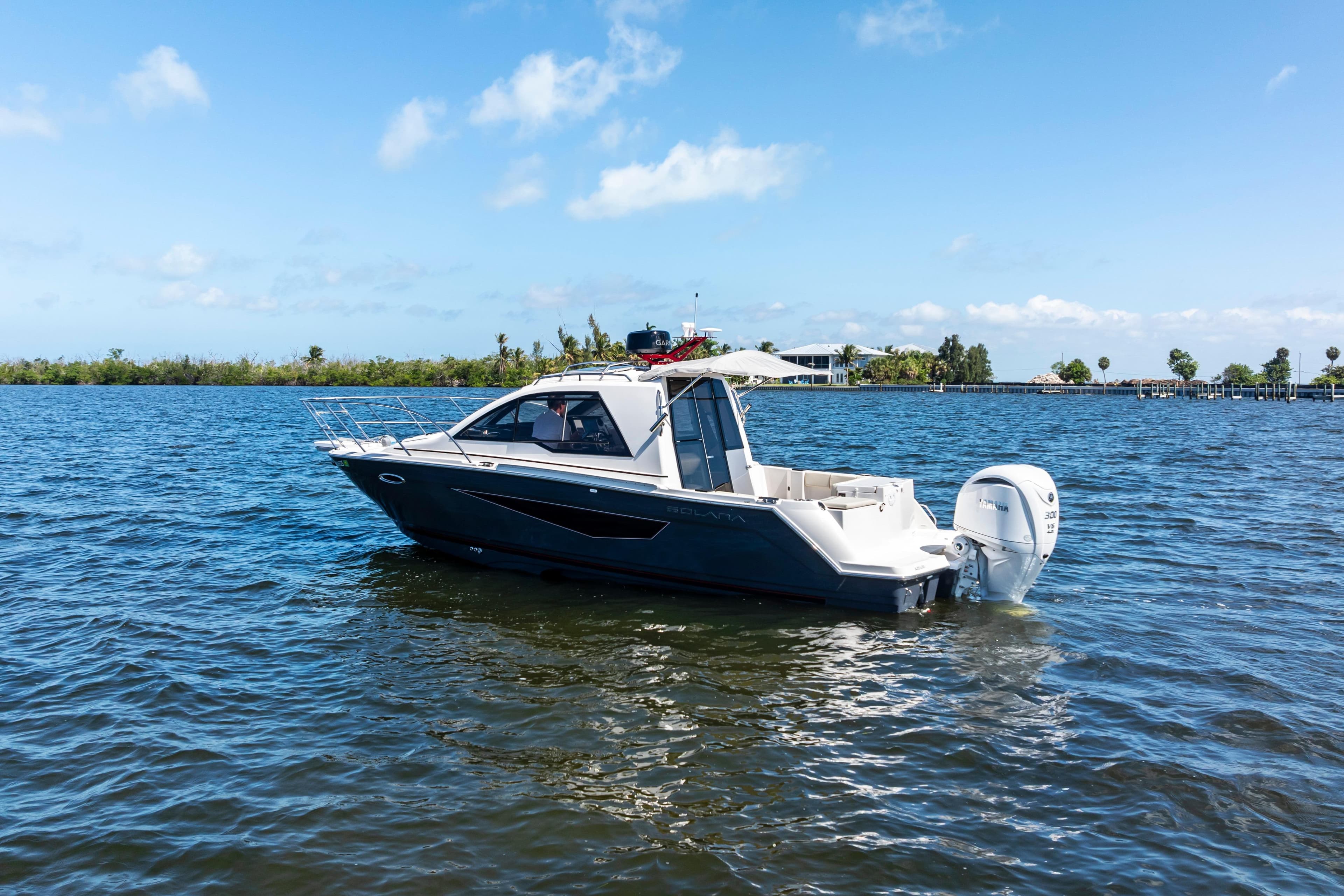 2026 Solara S-250 Coupe boat on calm water under clear blue sky.
