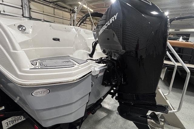 2023 NauticStar 243DC Sport Deck boat with Mercury outboard engine in a showroom.