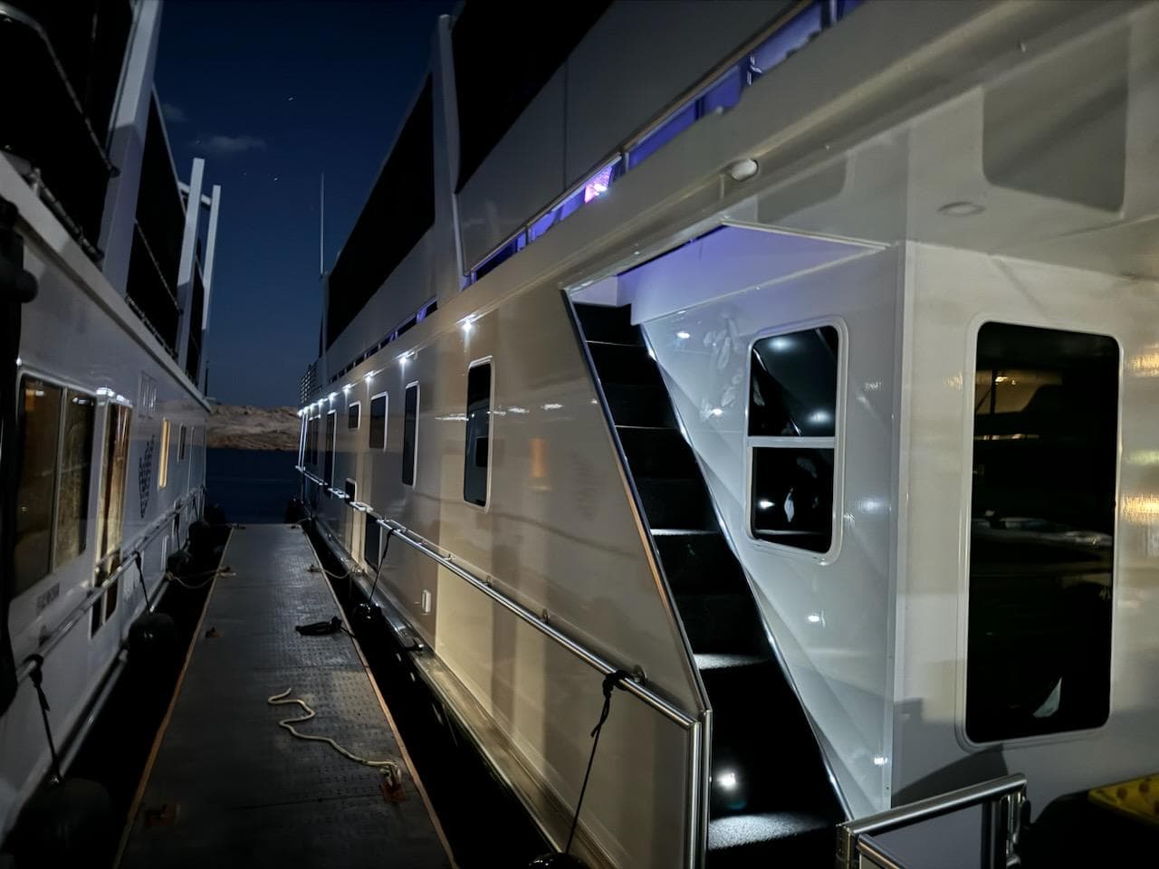 2024 Sumerset Limitless Share 10 houseboat docked at night with illuminated exterior.