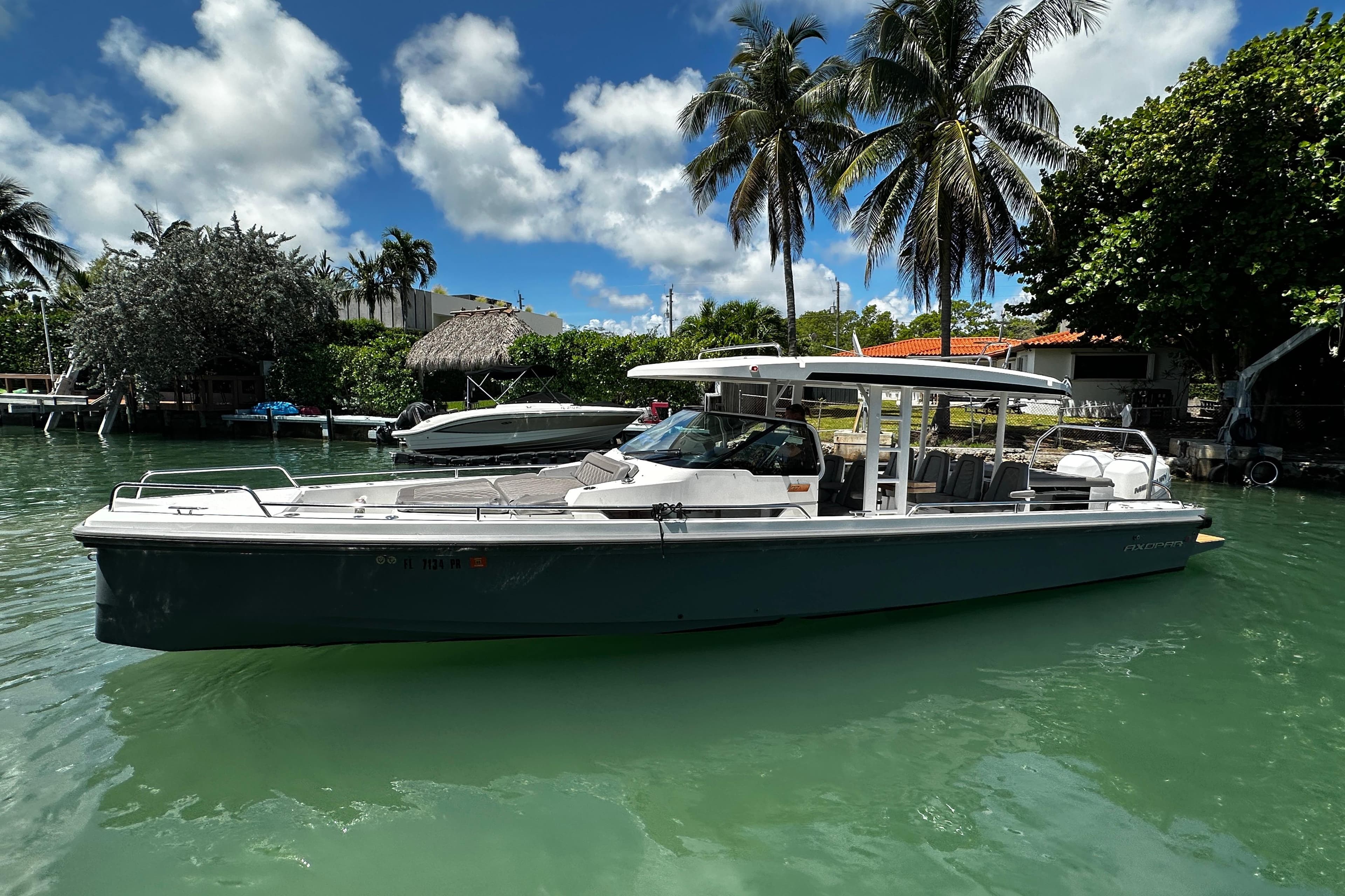 2018 Axopar 37 Sun-Top boat docked in tropical marina with palm trees.