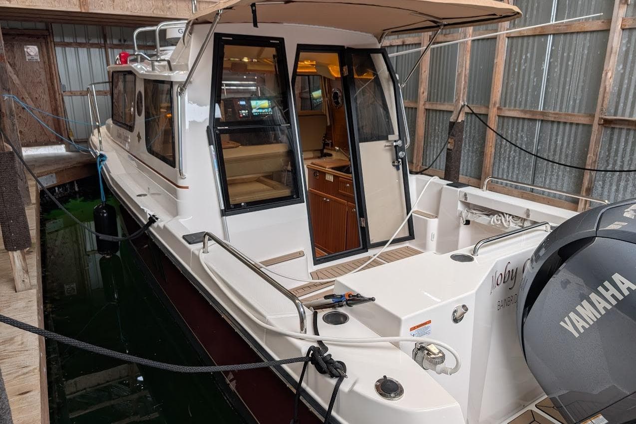 2024 Ranger Tug R25 boat docked in a covered marina, featuring Yamaha outboard motor.