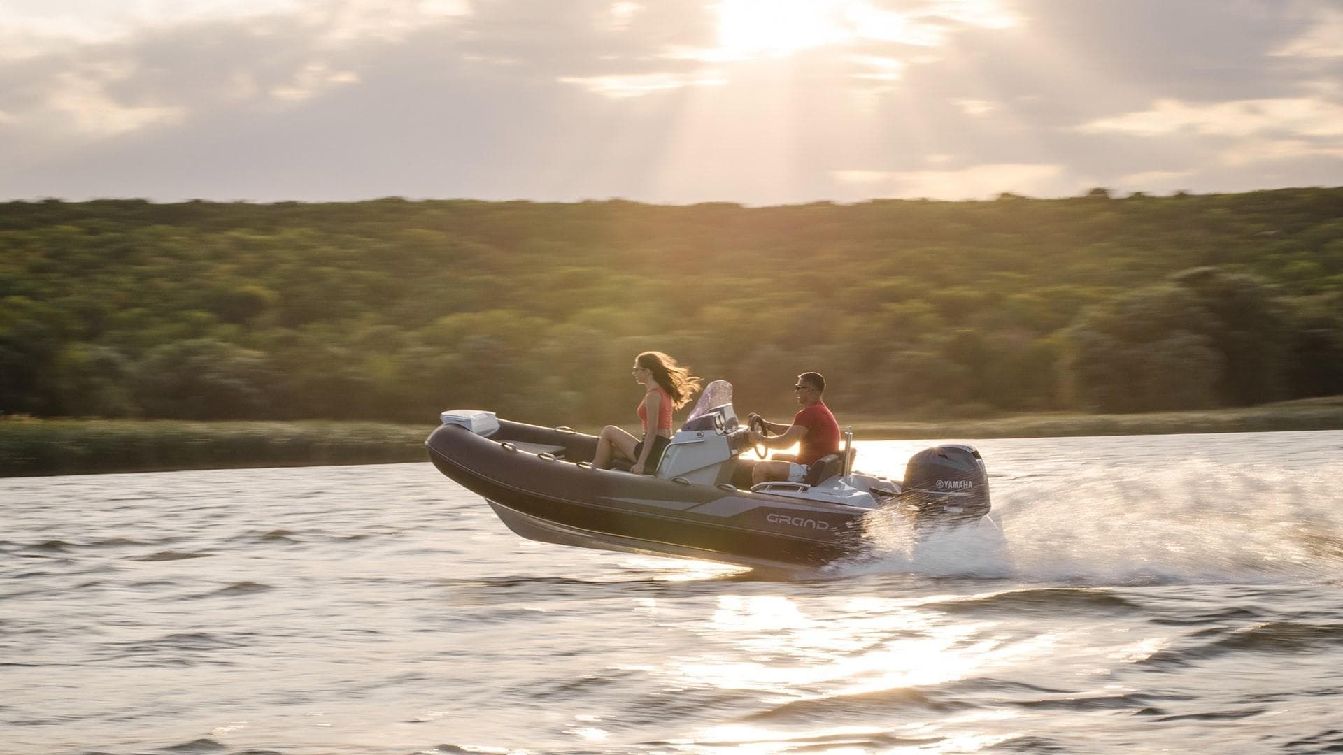 2025 Grand Inflatables G420 boat cruising on a lake at sunset.