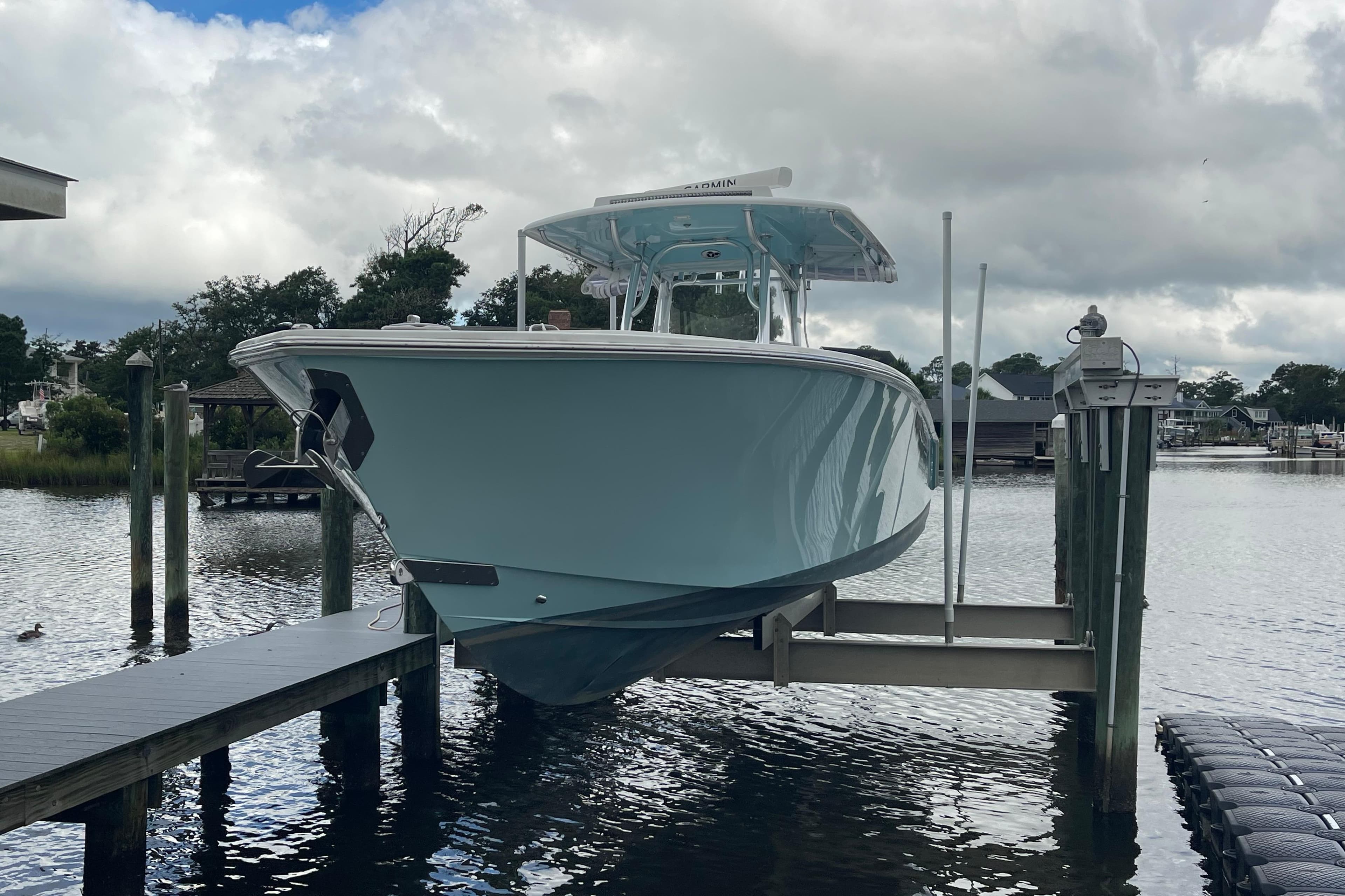 2020 Jupiter 38 boat on lift at dock, cloudy sky background.