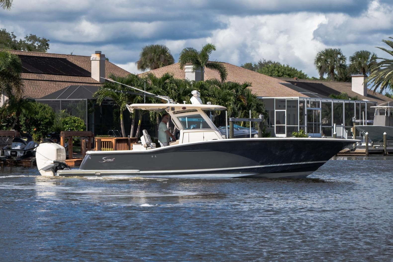 2019 Scout 320 LXF boat cruising on a scenic waterway near waterfront homes.