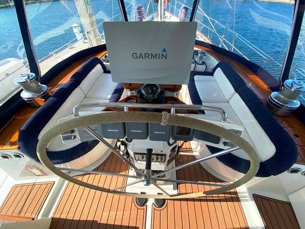 Cockpit of 1989 Irwin 54 yacht with Garmin navigation, wooden deck, and cushioned seating.