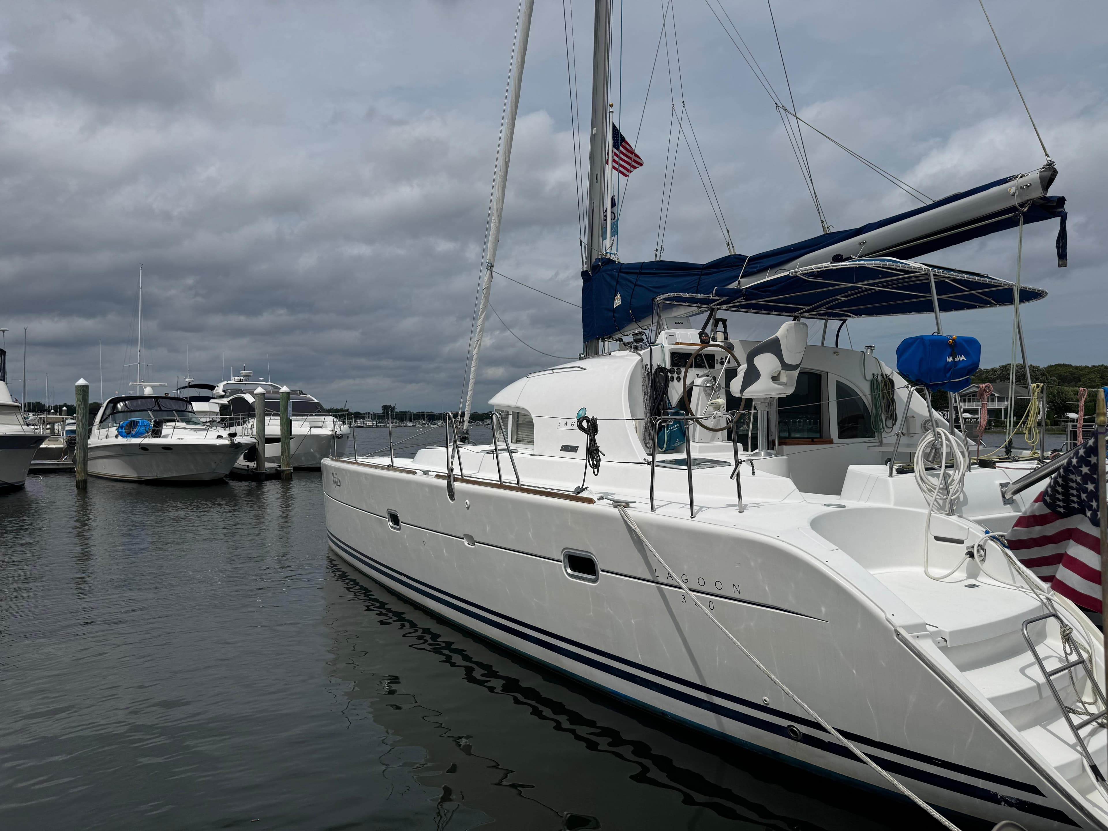 2000 Lagoon 380 catamaran docked in a marina, with cloudy skies and nearby boats.
