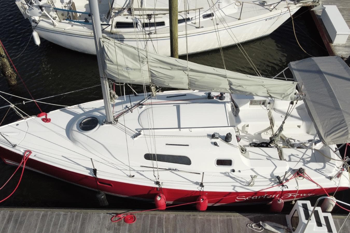 2006 Hunter 27 sailboat docked, featuring a red hull and white deck.