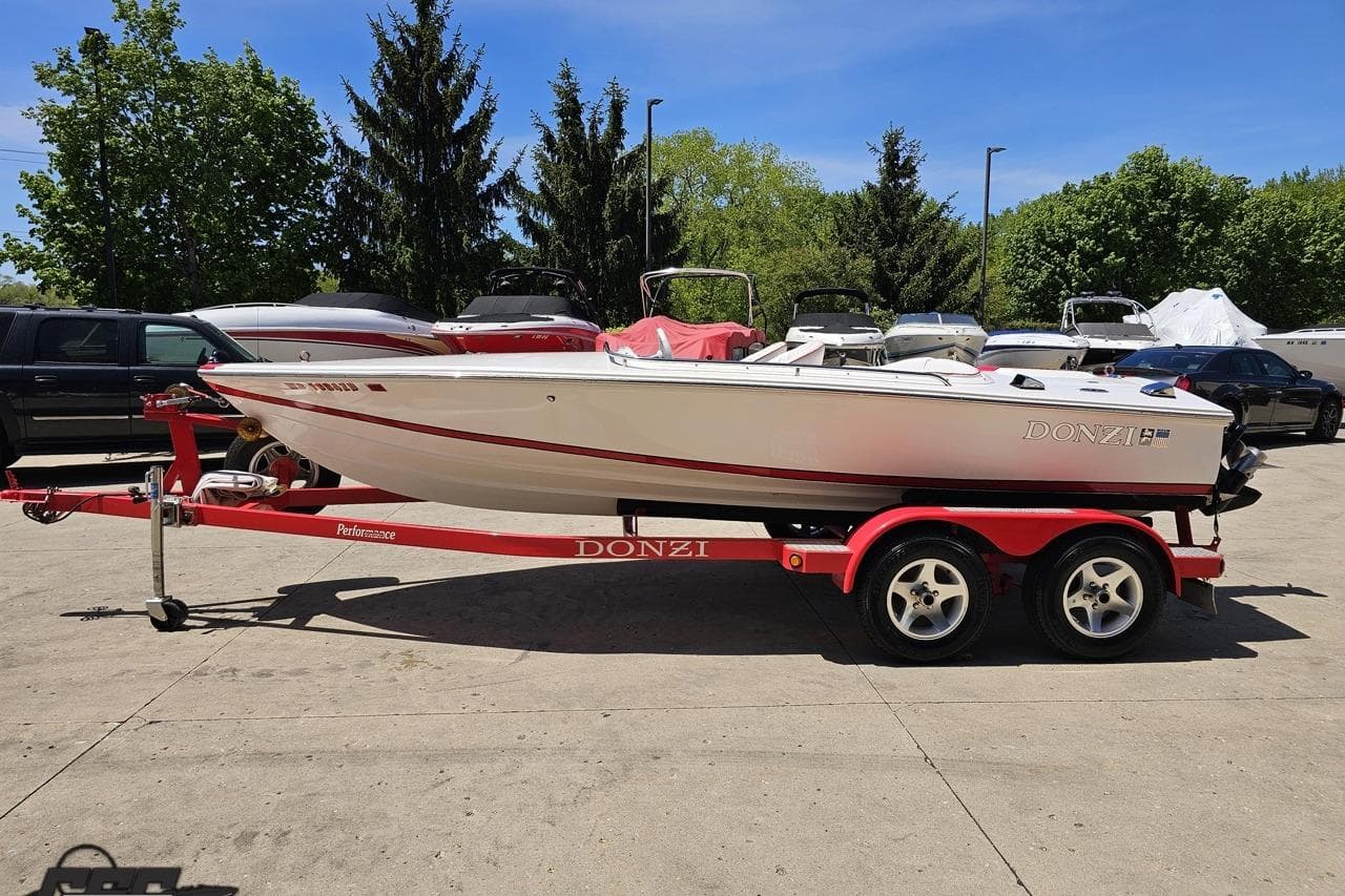 1997 Donzi 18 Classic boat on a red trailer, parked outdoors.