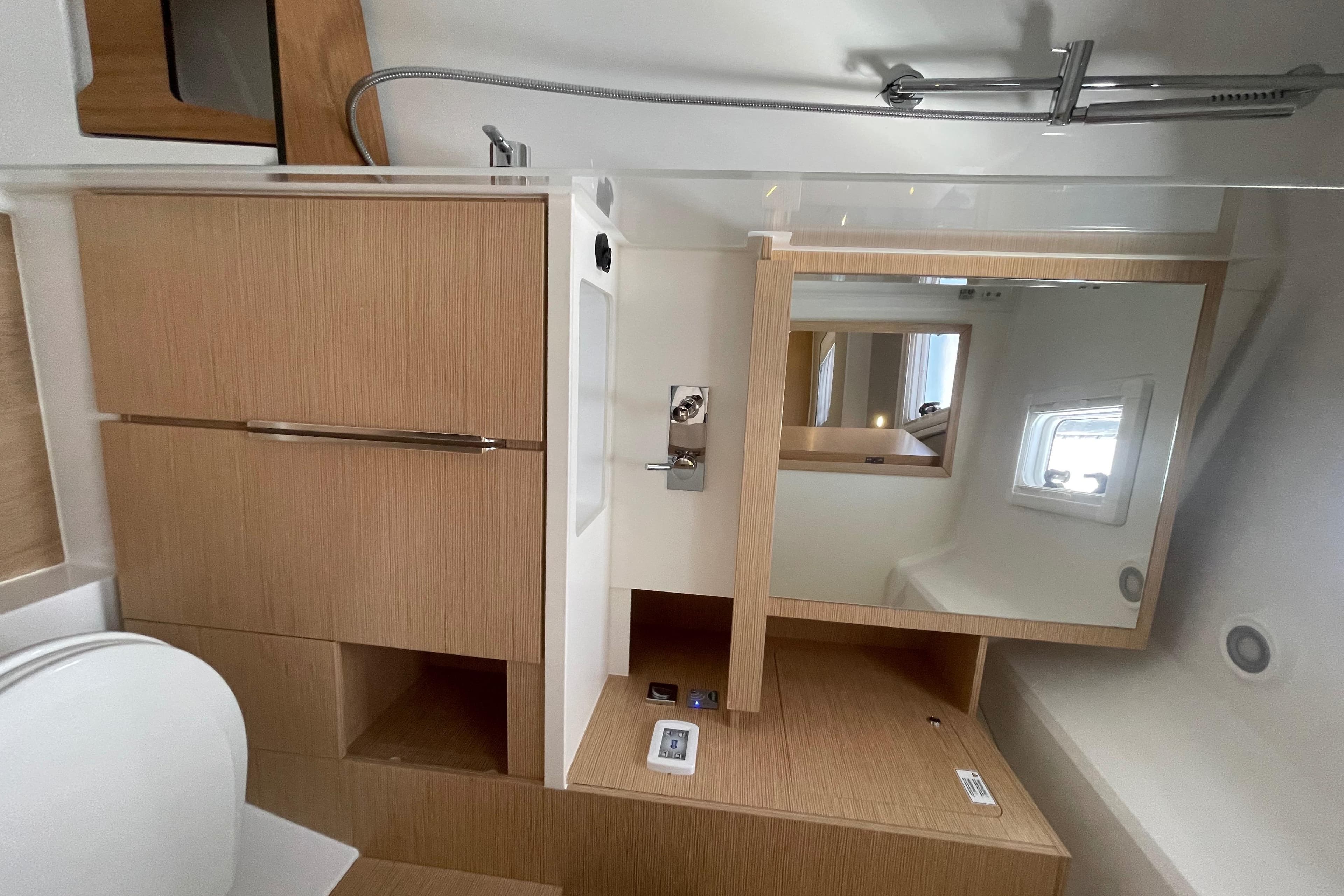 Modern bathroom interior of 2023 Hanse 460 yacht with wooden cabinetry and mirror.