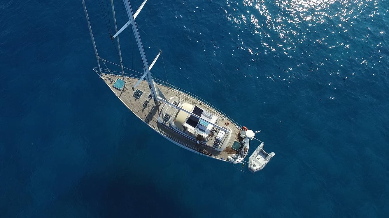 Aerial view of 1987 Standfast 50 yacht sailing on clear blue ocean waters.