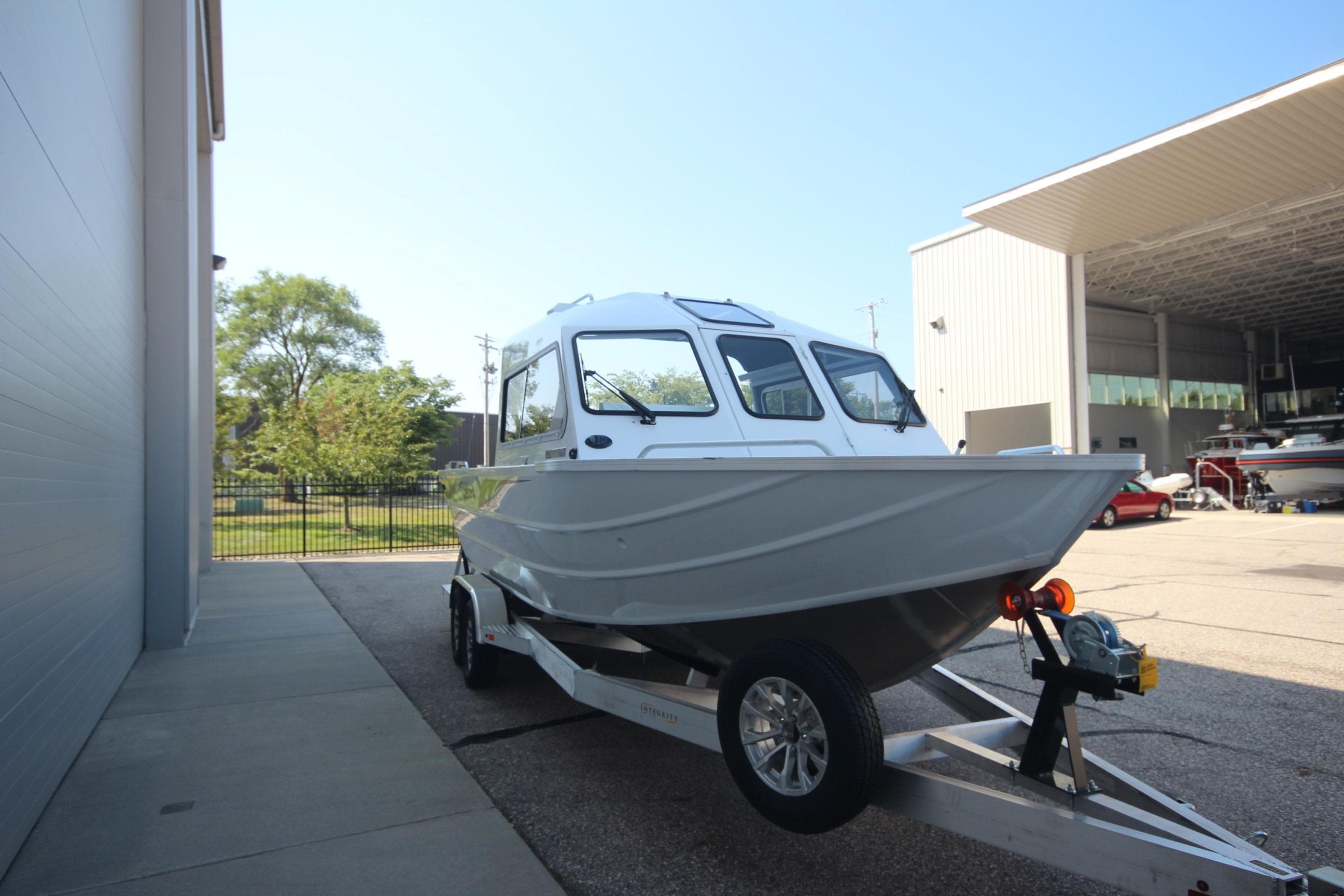 2026 Weldcraft 220 Maverick DV 250hp boat on trailer, parked outside a building.