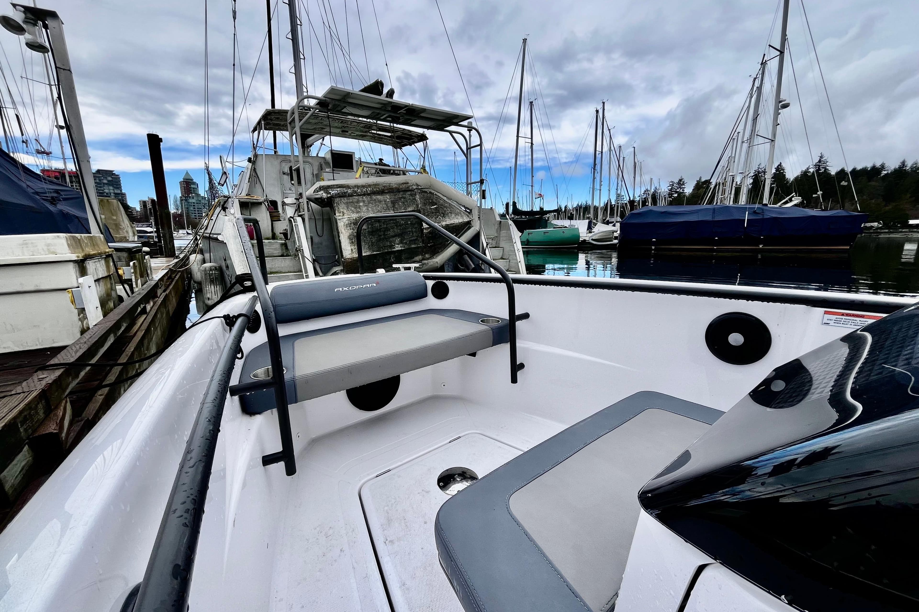 2023 Axopar 22 T-Top boat docked in a marina with sailboats.