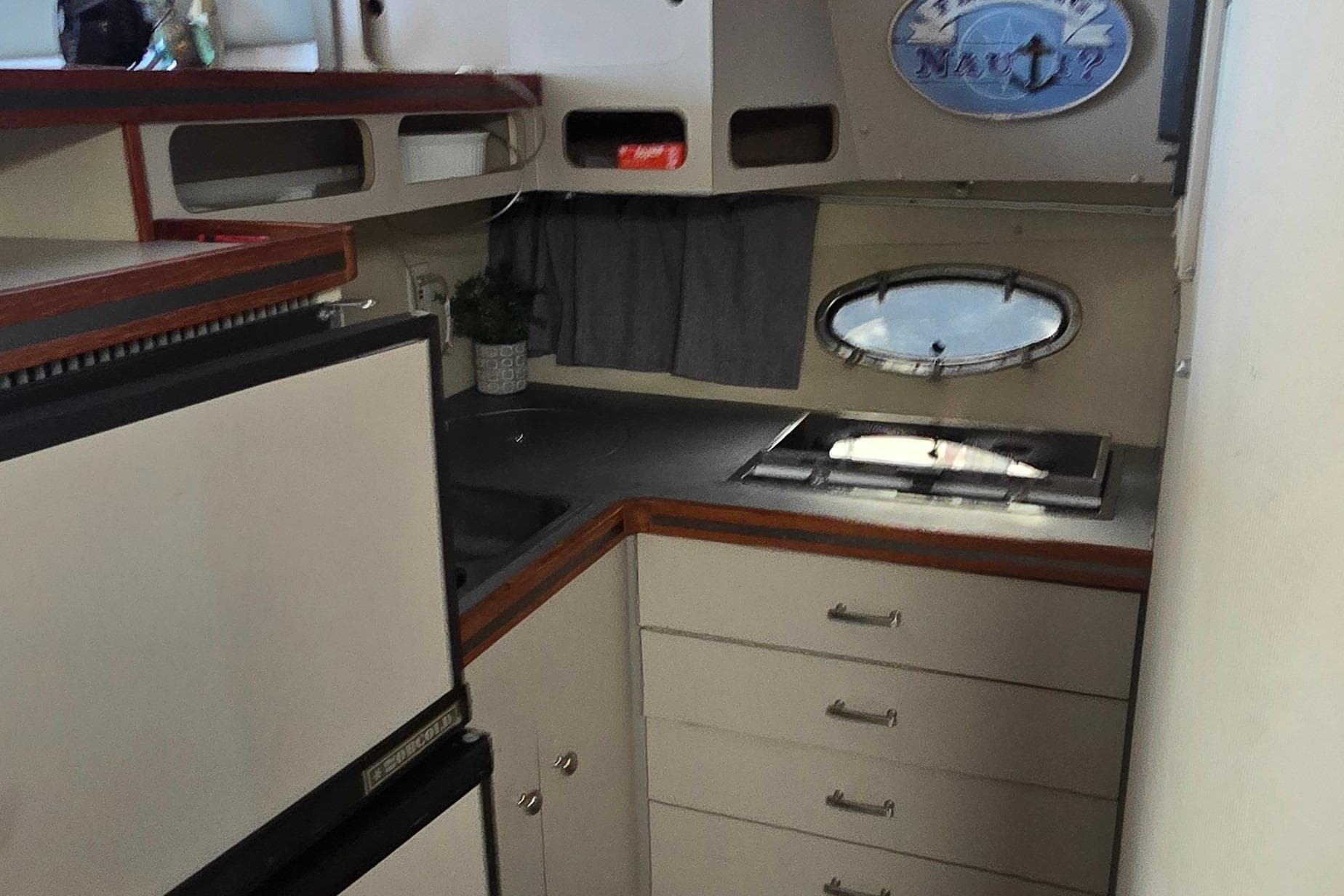 1987 Trojan 10.8 Meter Sedan yacht interior with kitchenette and porthole window.