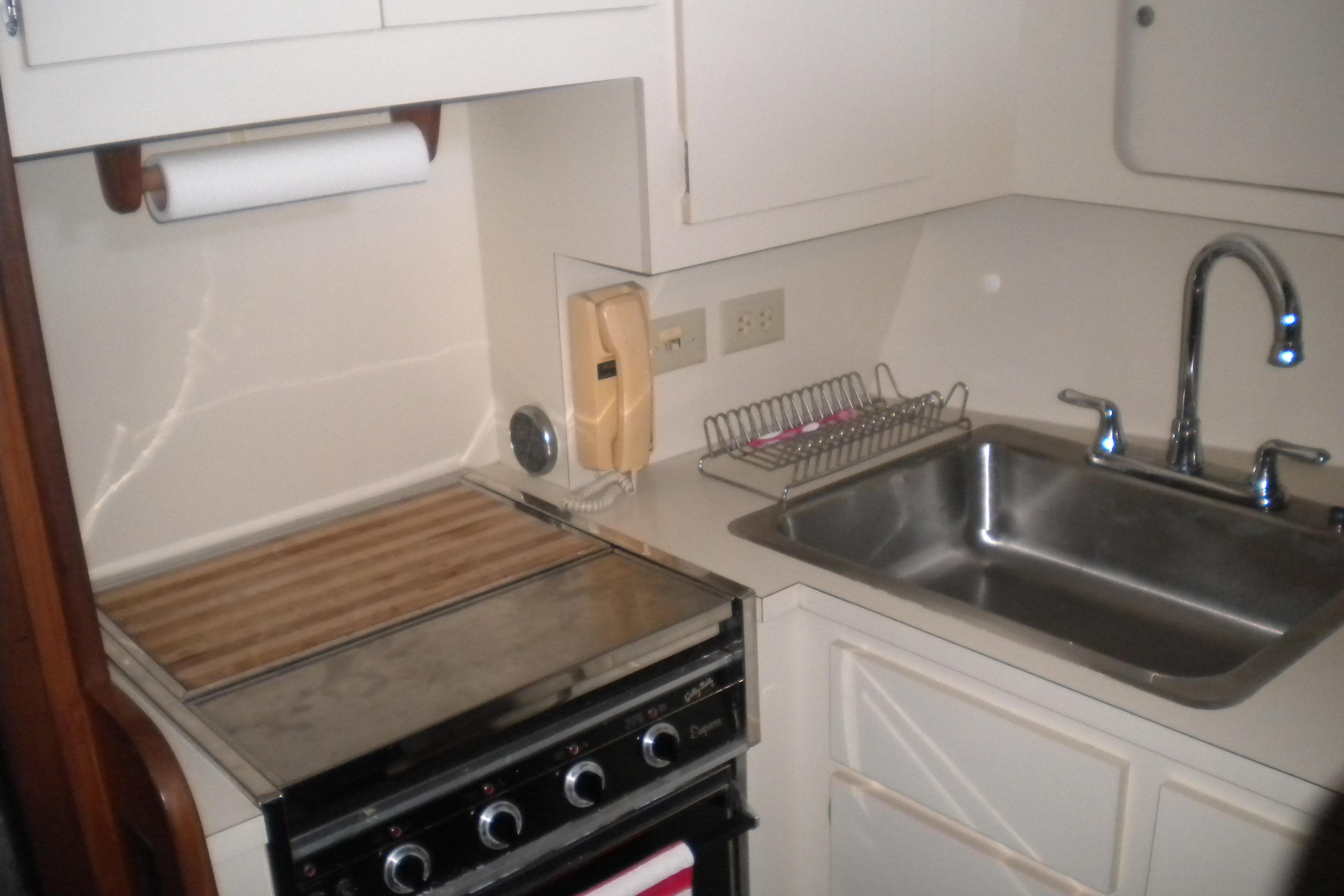 Compact kitchen area in a 1987 Hatteras 40 Motor Yacht with stove and sink.