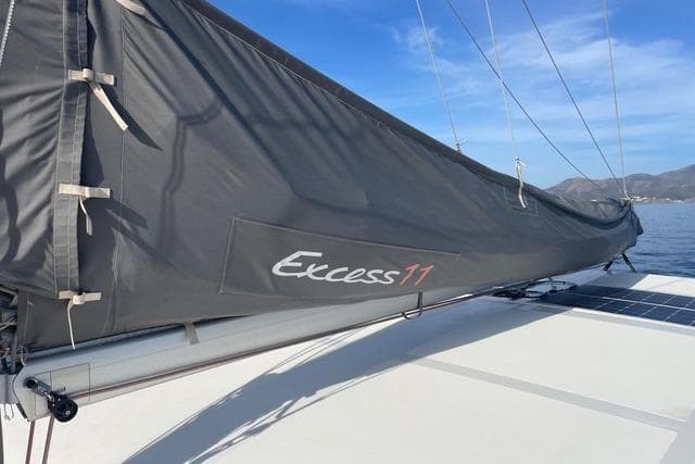 Sailboat with Excess 11 branding, 2021 model, on calm water under blue sky.