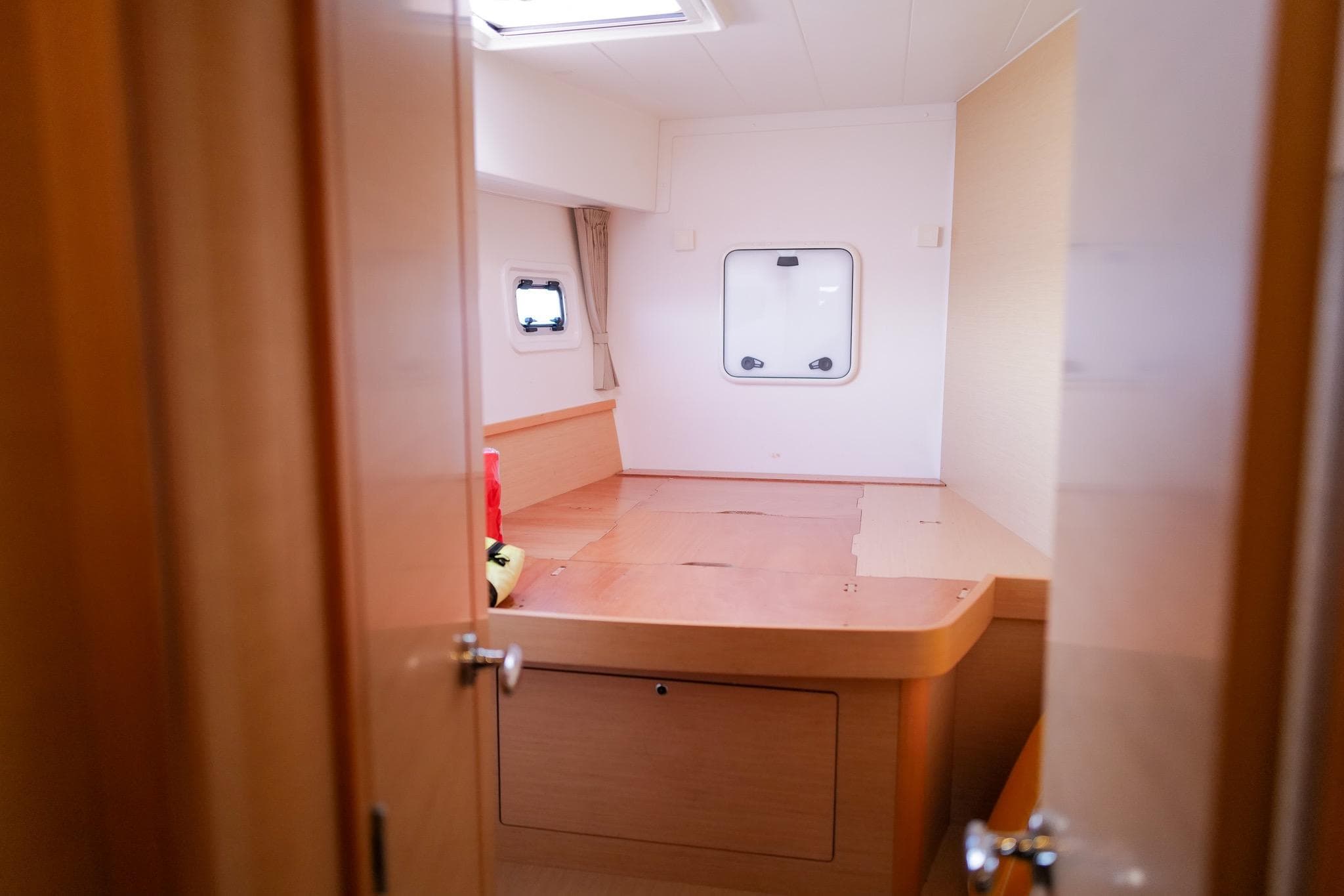 Interior cabin of a 2018 Lagoon 42 catamaran, featuring wooden furnishings and a window.