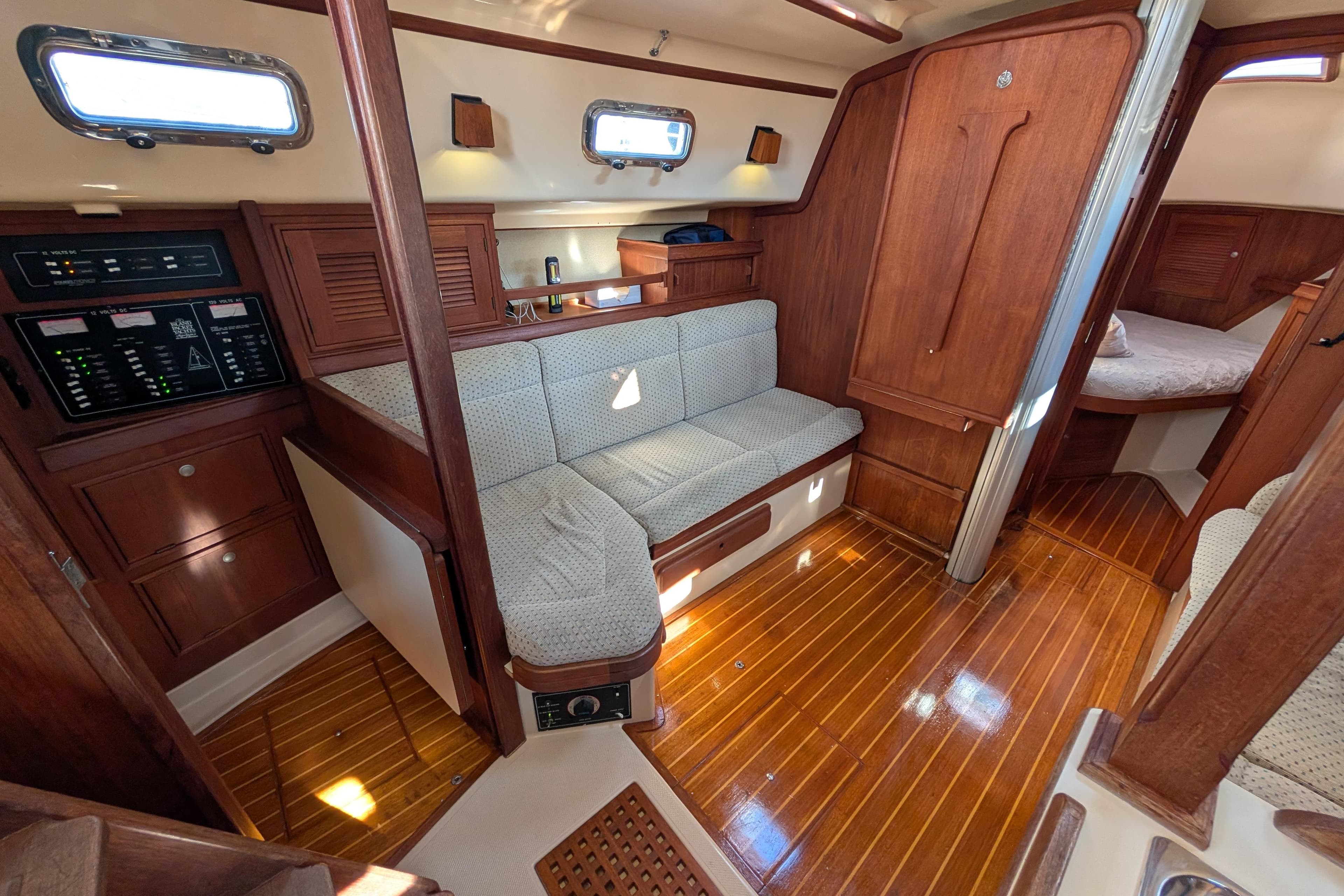 Interior of 1999 Island Packet 320 sailboat with wooden finishes and cozy seating area.