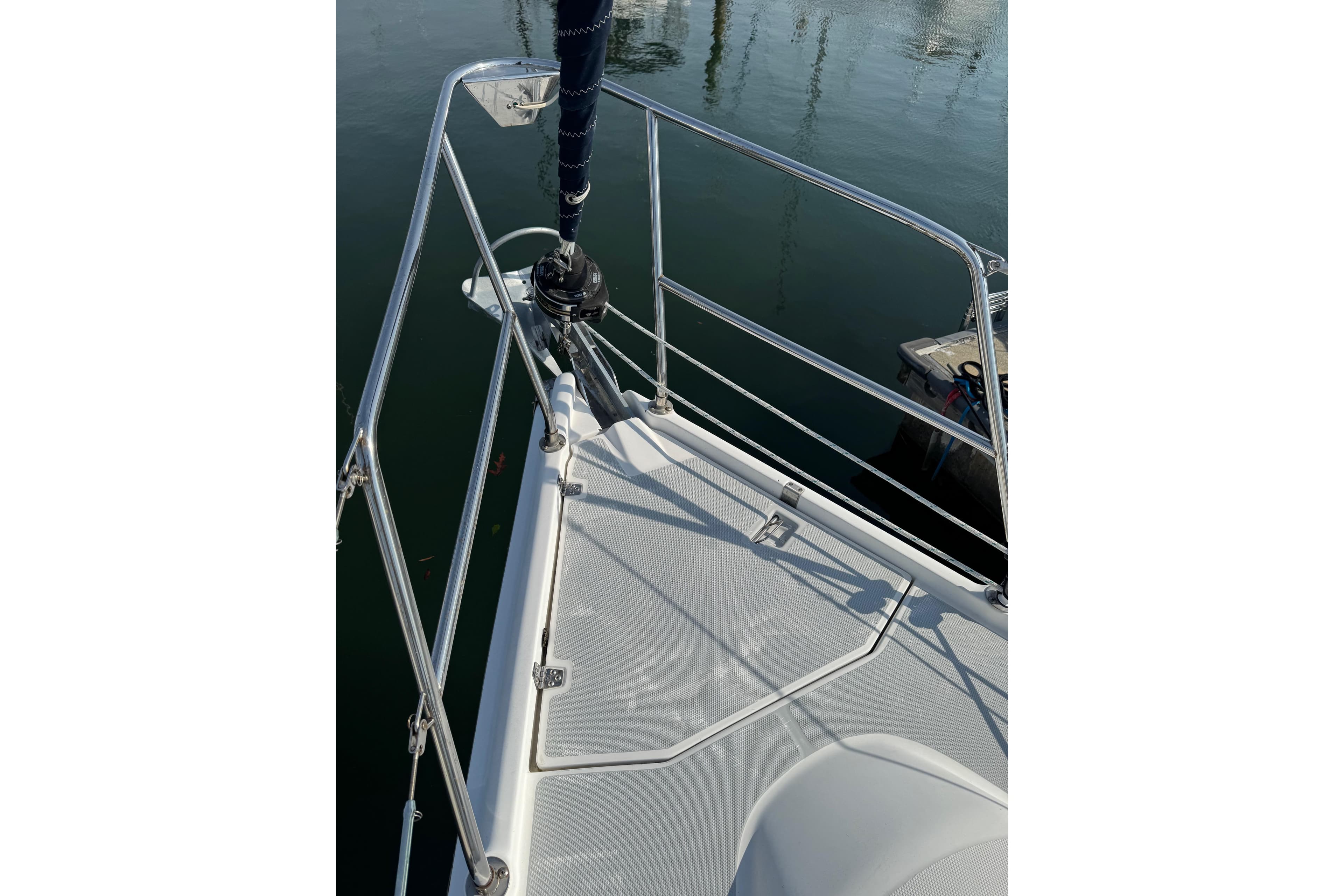 Bow of a 2002 Hunter 326 sailboat with stainless steel railings and calm water reflection.