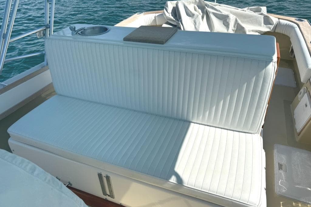 White cushioned seating on 1986 Dusky 26 Custom boat, with ocean backdrop.