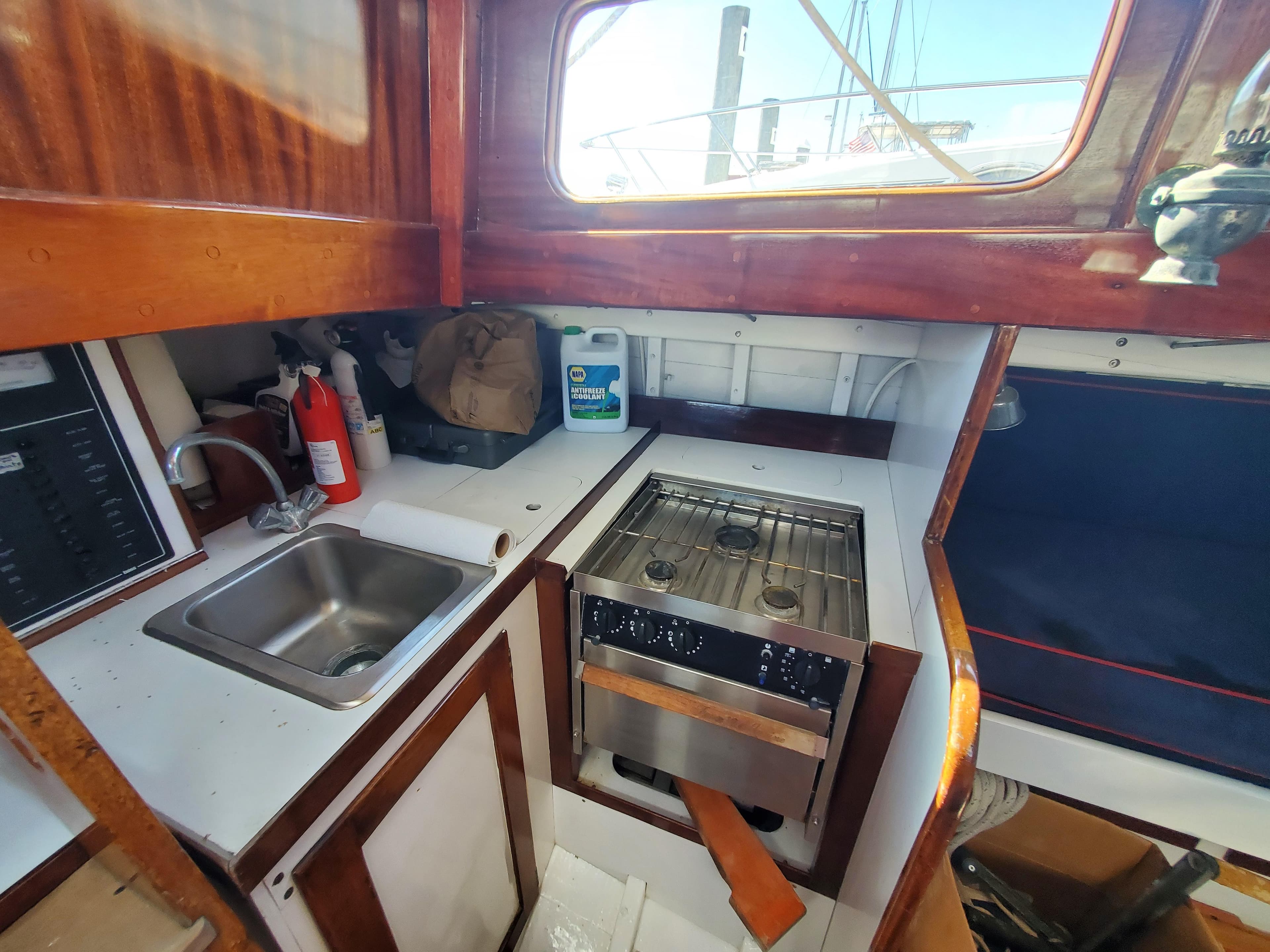 1958 Custom Larson 40 yacht kitchen with sink, stove, and wooden cabinetry.