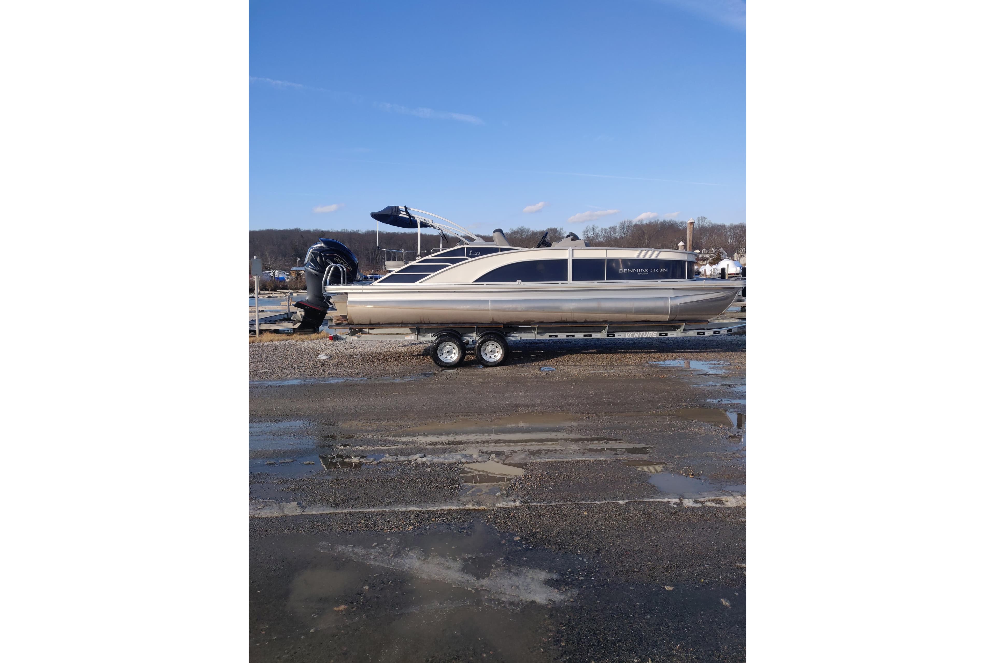 2023 Bennington 23LTSB pontoon boat on trailer, parked outdoors under clear sky.