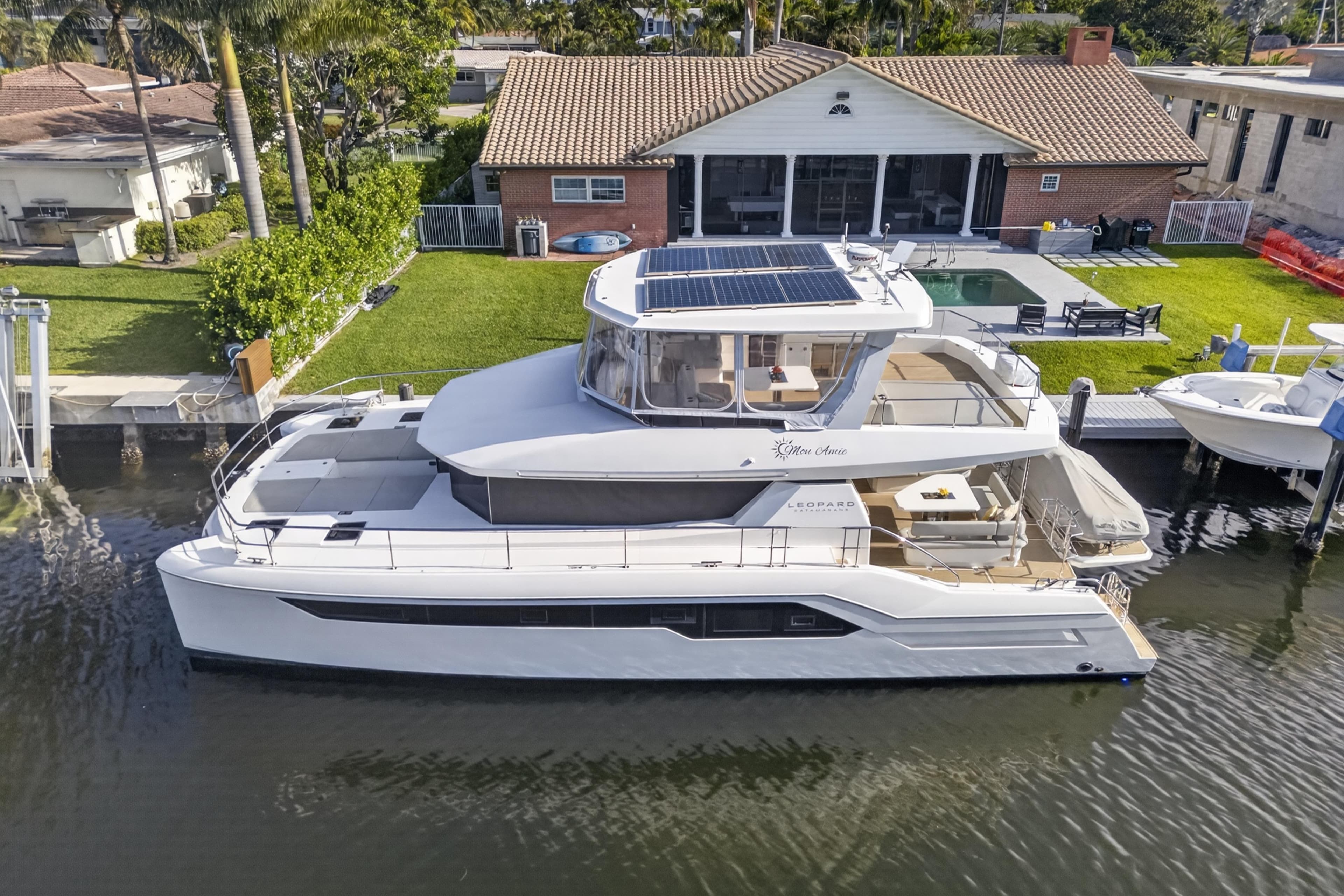2022 Leopard 53 Powercat yacht docked by a waterfront home.