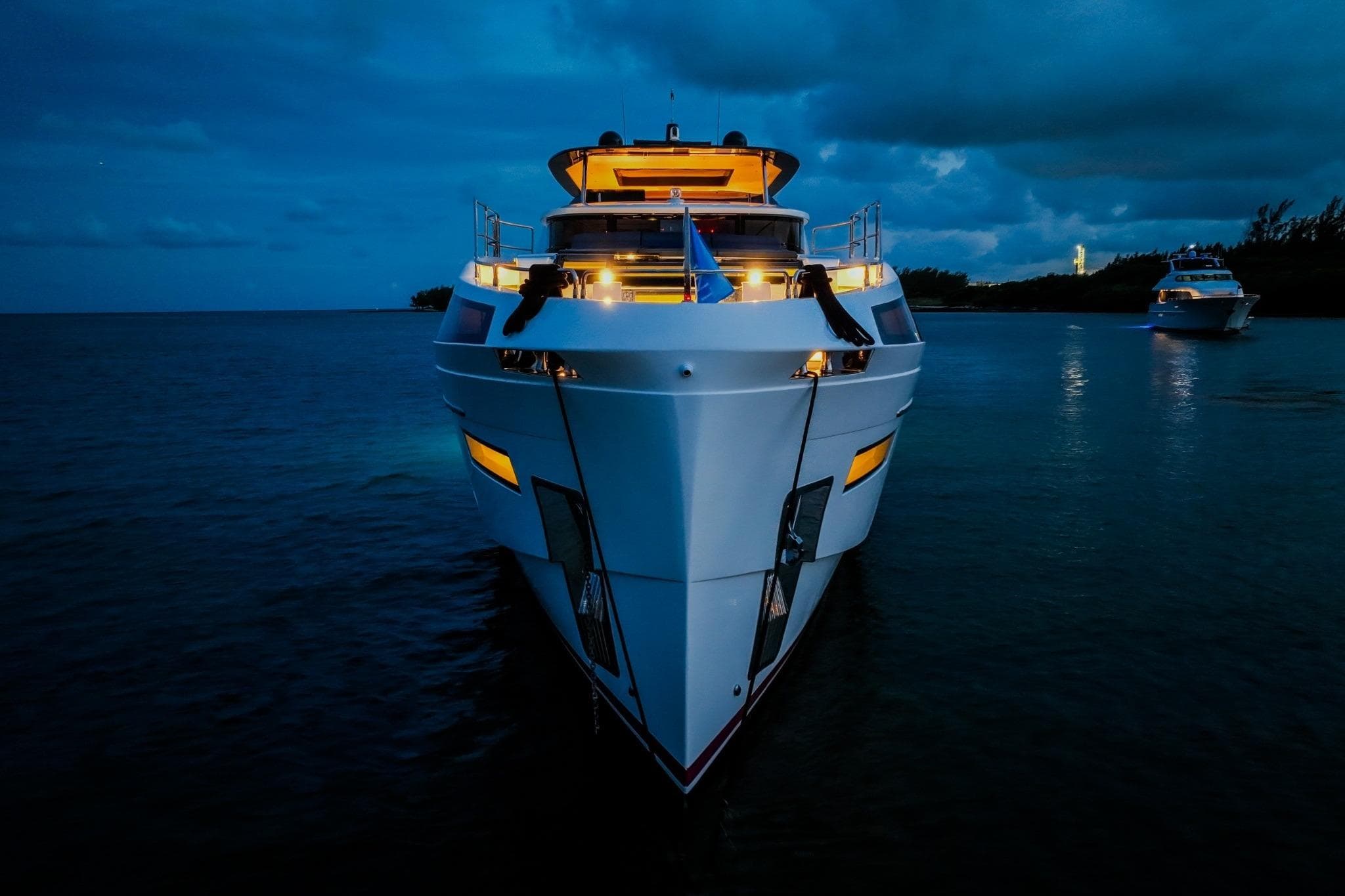 Luxurious 2021 Sirena 88 yacht illuminated at dusk on calm waters.