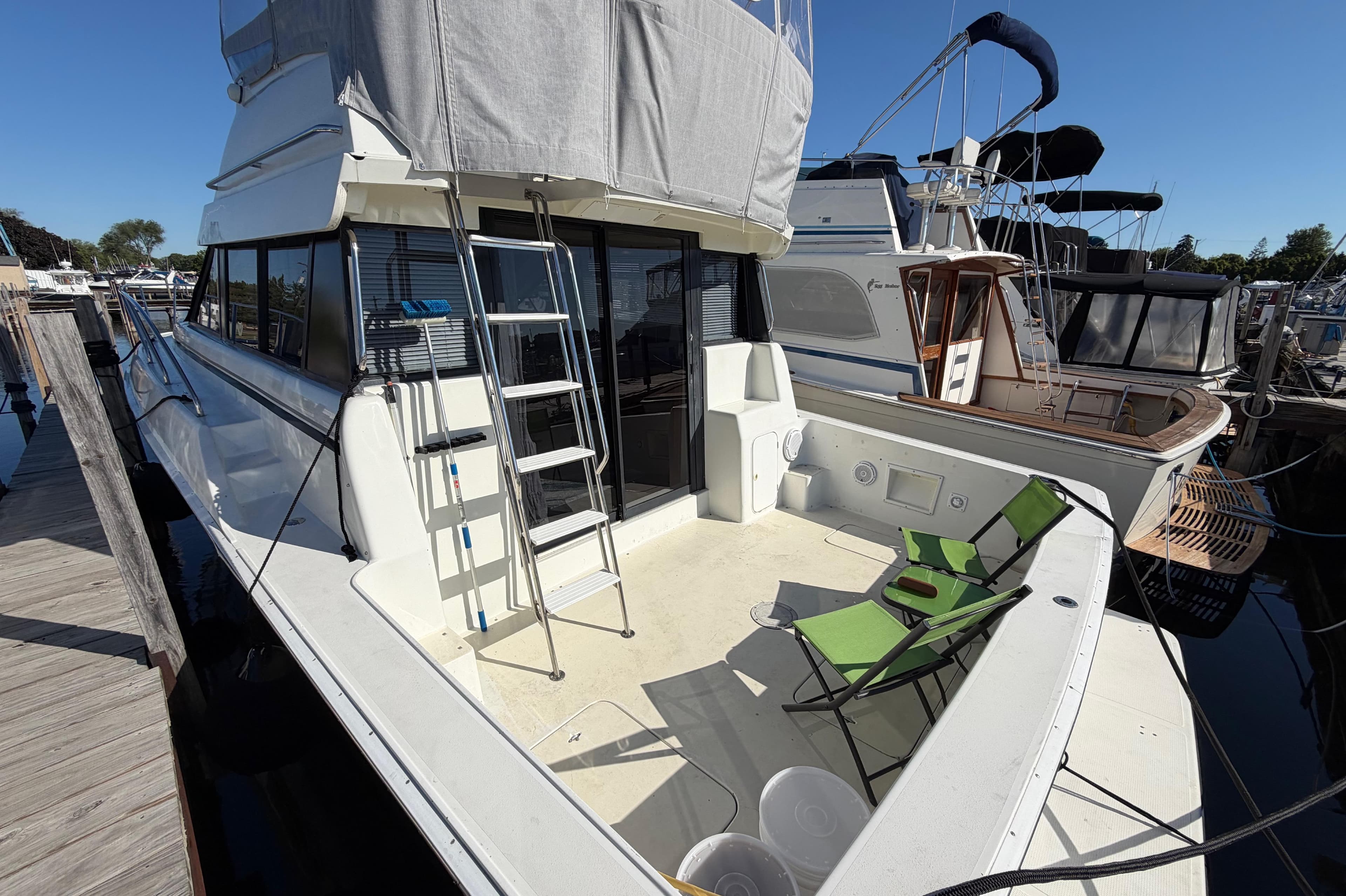 1995 Silverton 37 Convertible yacht docked with green chairs on deck.