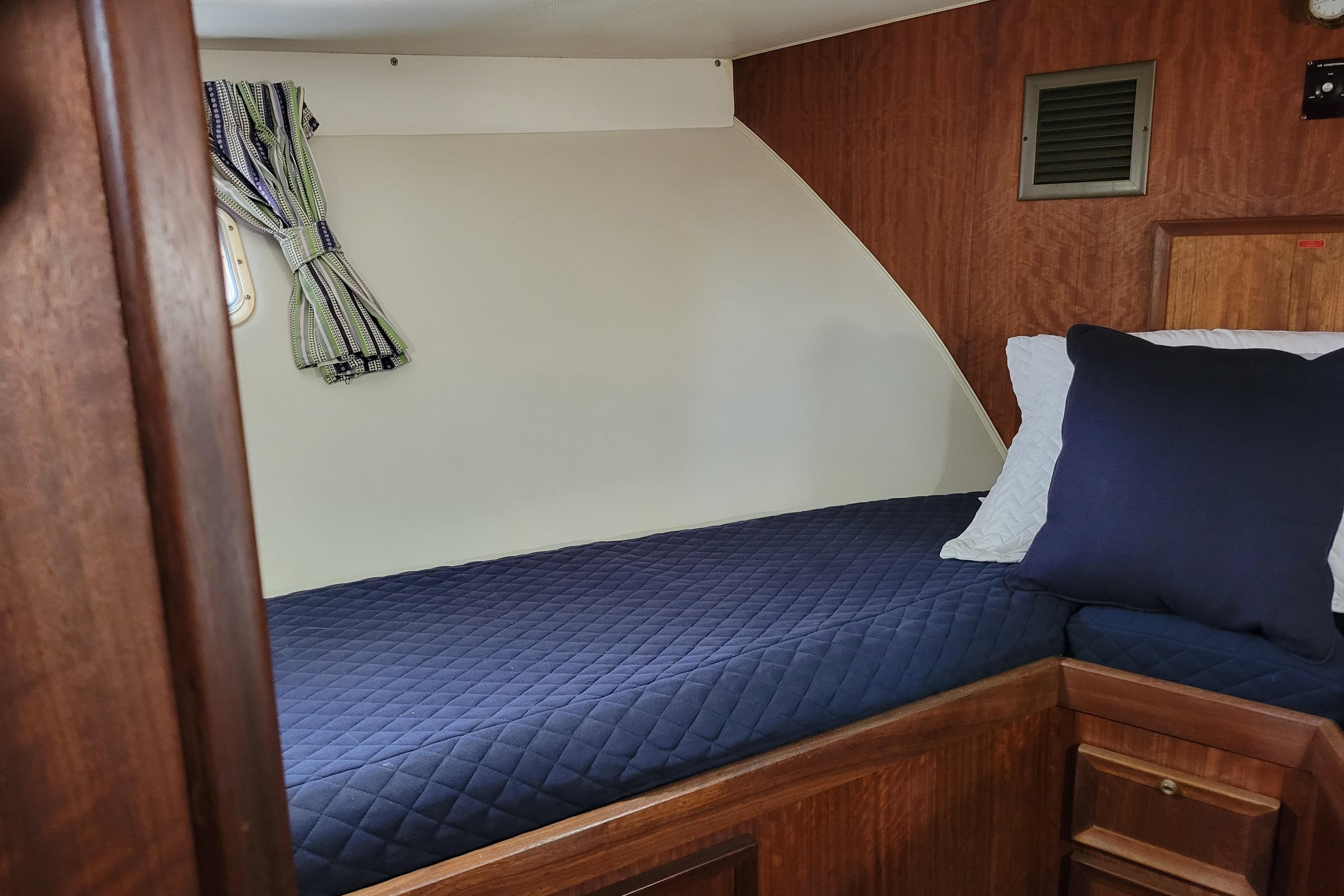 1977 Hatteras 43 Double Cabin interior with blue bedding and wooden accents.