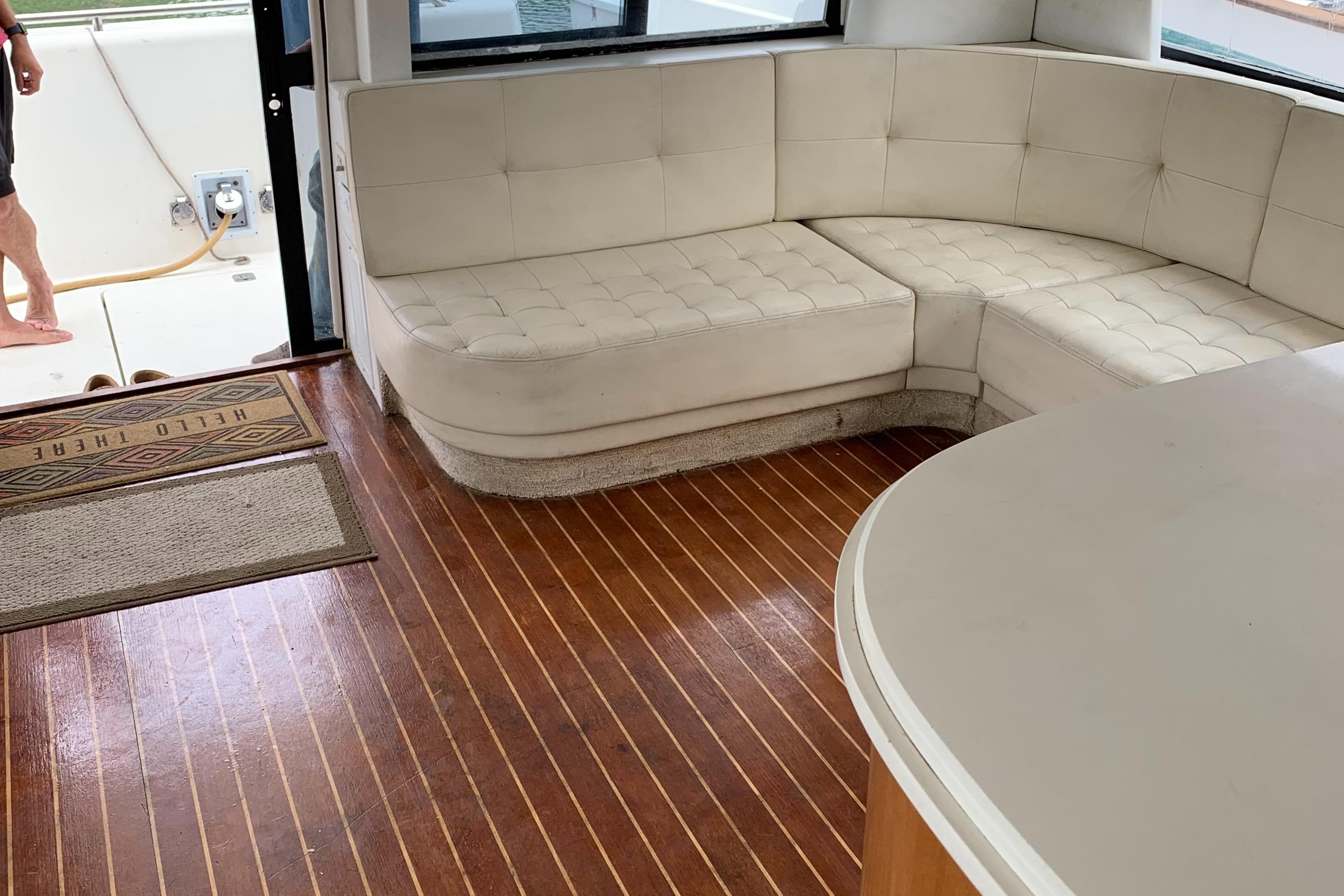 1999 Bayliner 5788 Pilot House Motoryacht interior with white seating and wooden flooring.