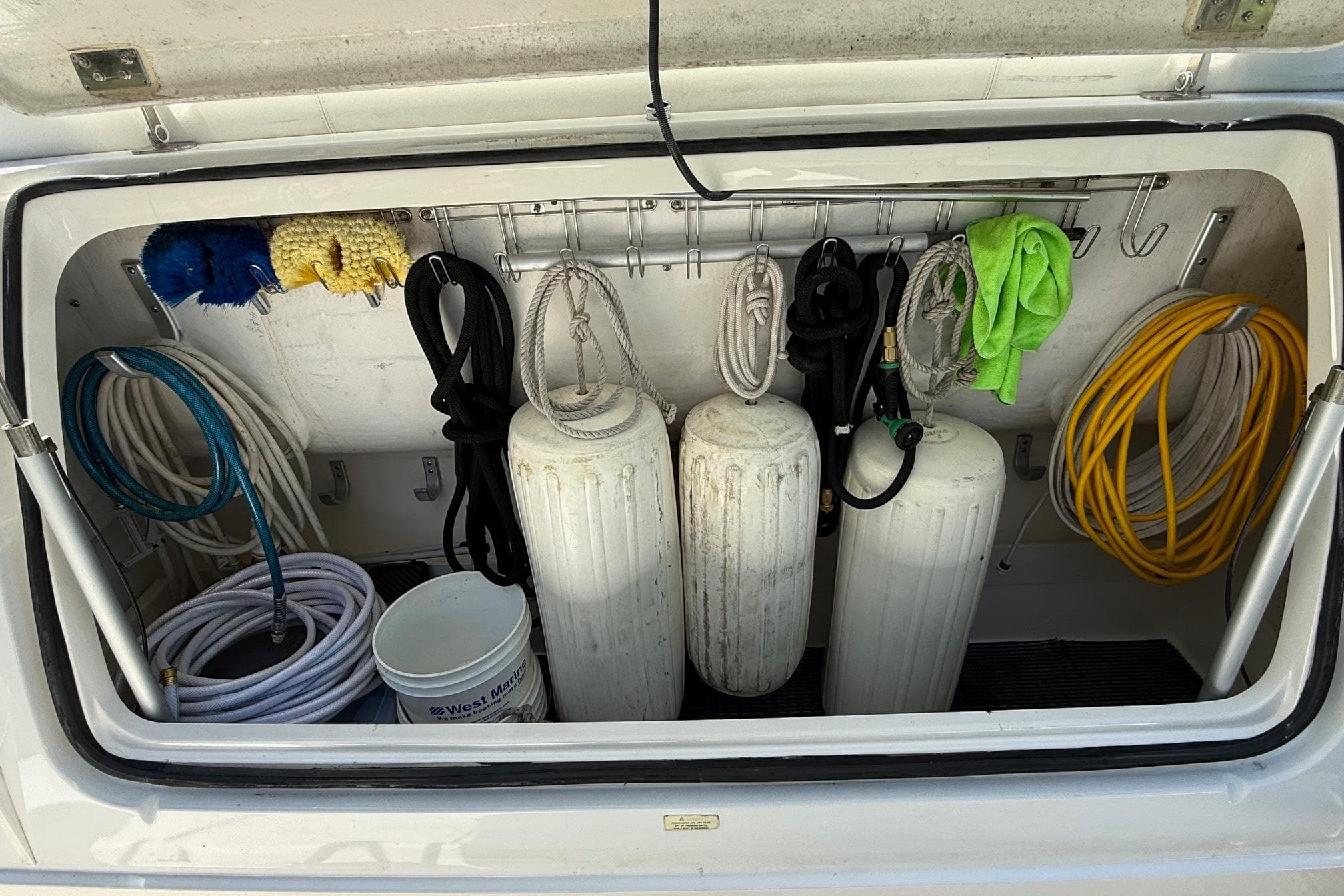 Storage compartment of a 2001 Tiara Yachts 5200 Express with ropes, fenders, and cleaning supplies.