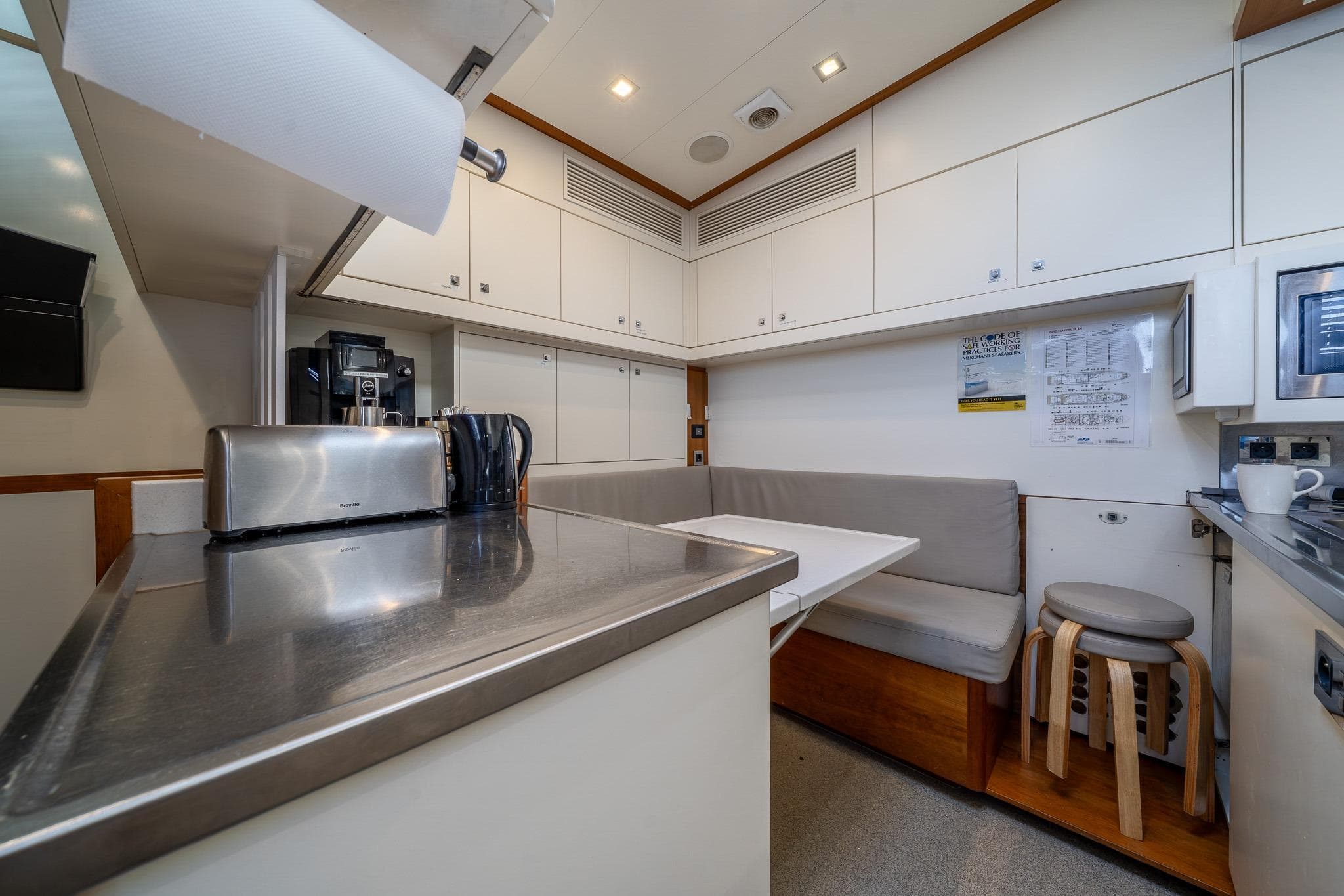 Modern kitchen area on a 2011 Guy Couach 121' yacht, featuring sleek cabinetry and seating.
