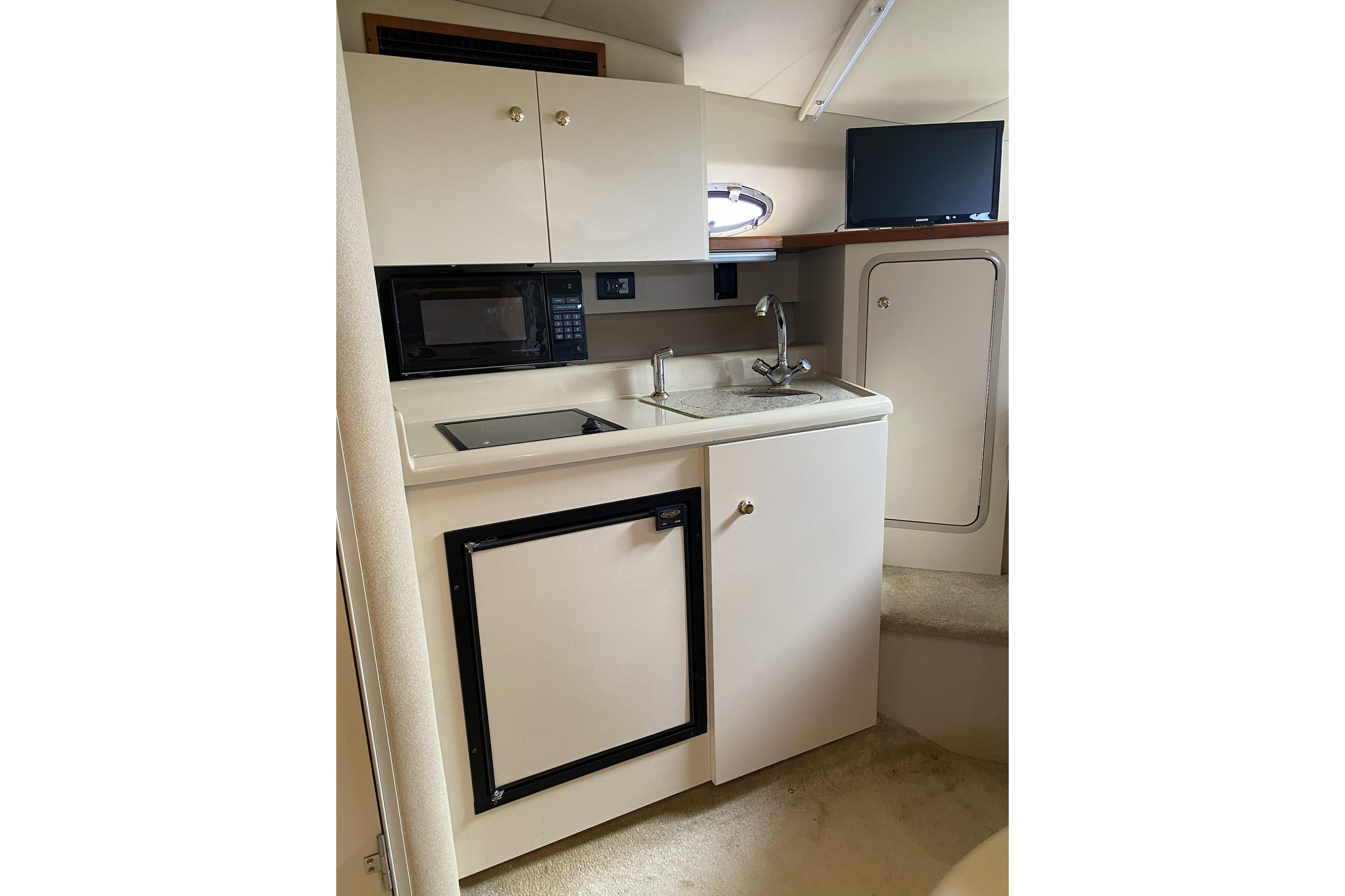 2003 Cruisers Yachts 2870 Express interior kitchen with microwave, sink, and compact fridge.