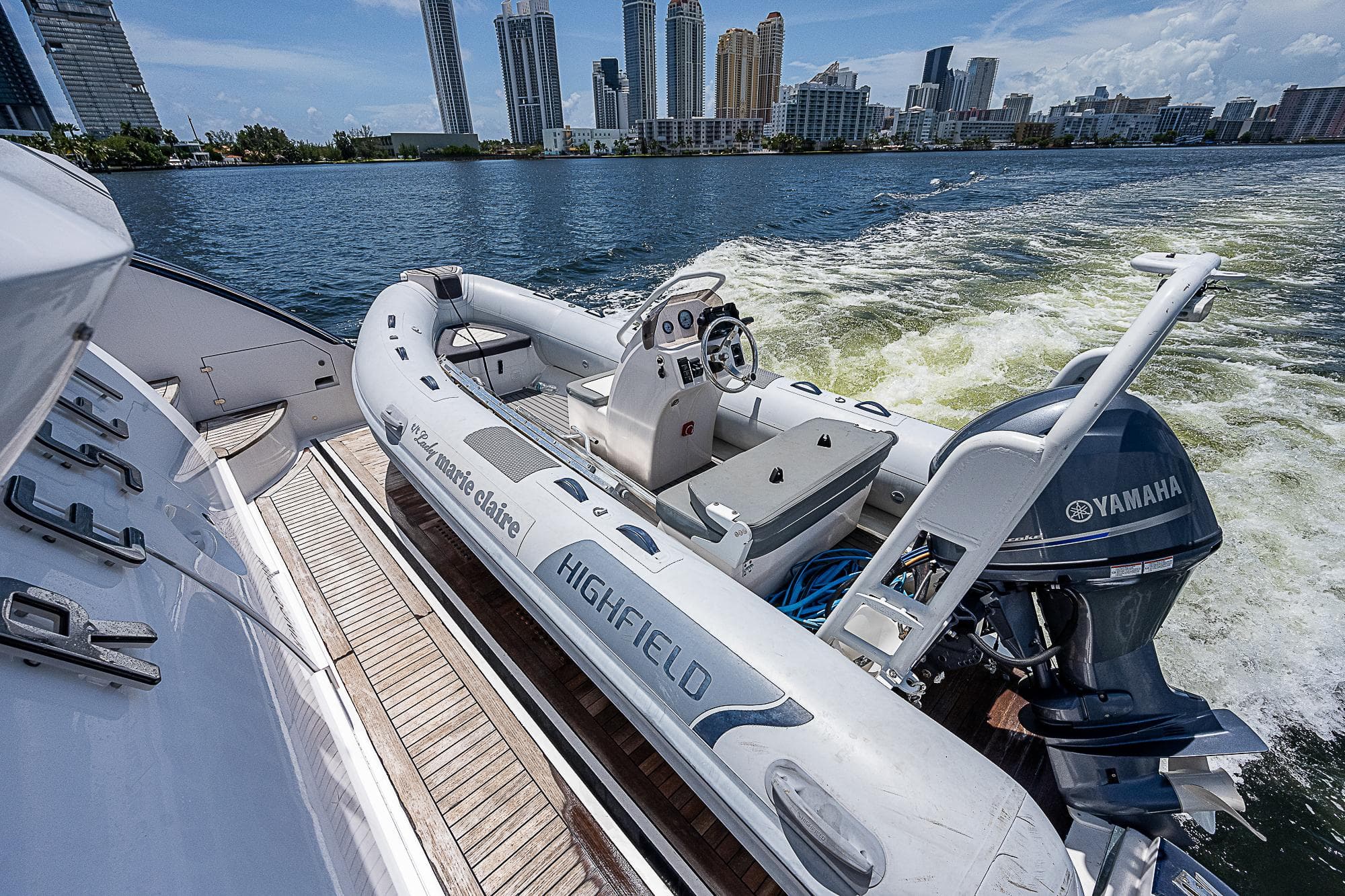 Azimut 82 yacht with Highfield tender and Yamaha engine, city skyline in background.