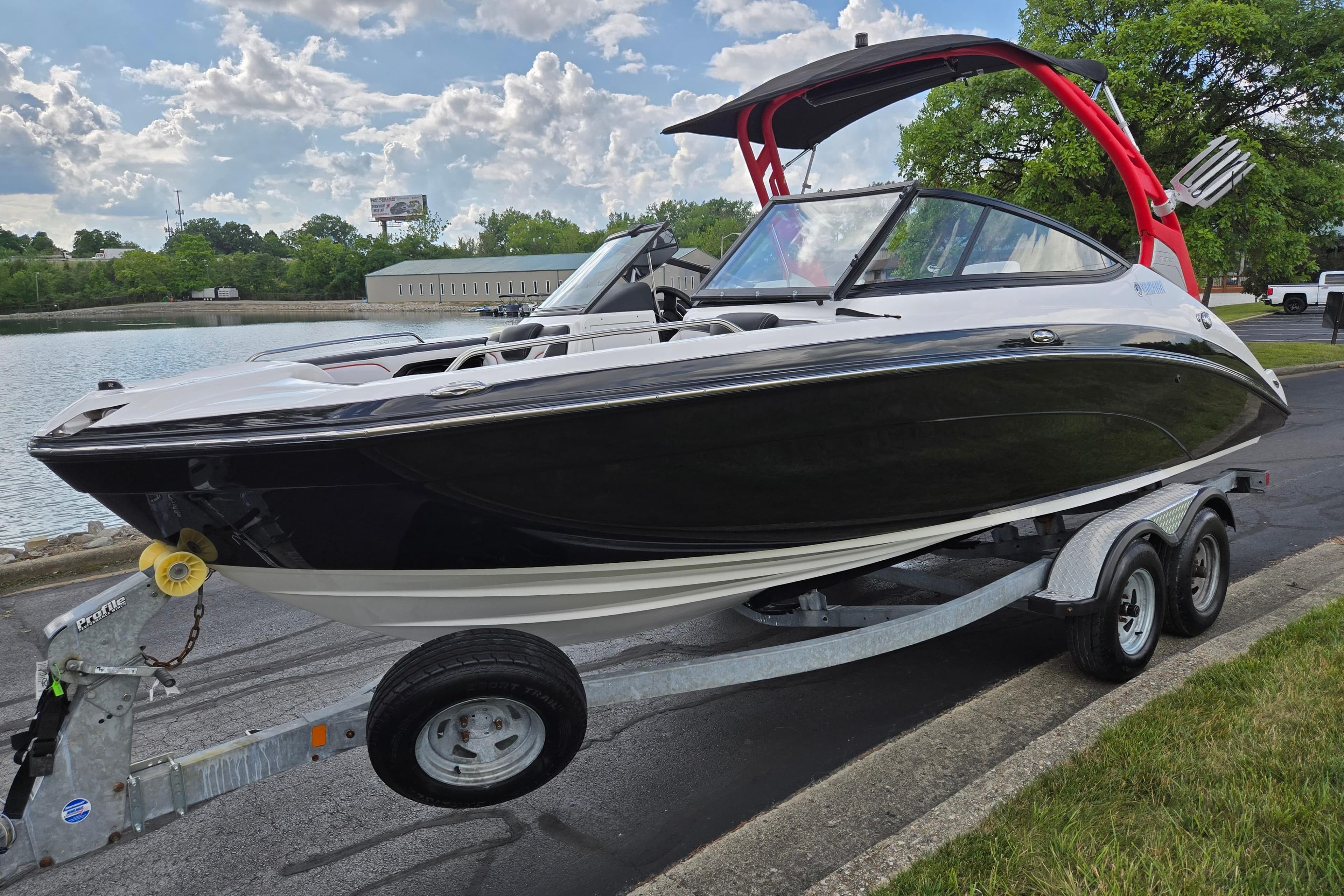 2018 Yamaha Boats 212X on trailer by a lake, featuring sleek black design.
