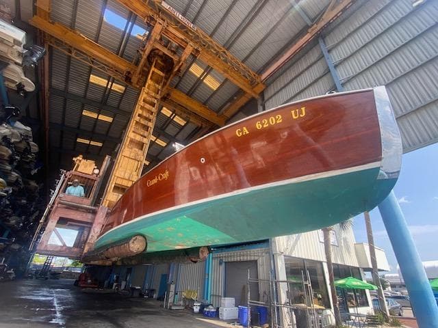 Grand Craft Classic Runabout 2000 in a boatyard, suspended for maintenance or storage.