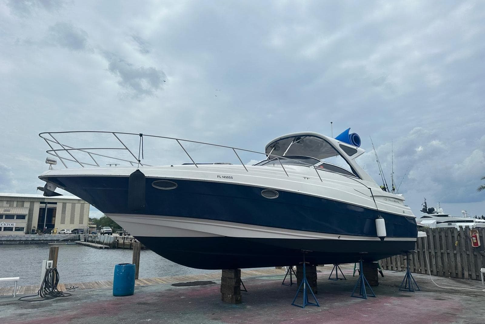 2008 Regal 38 Express boat on dry dock, blue and white hull, cloudy sky background.