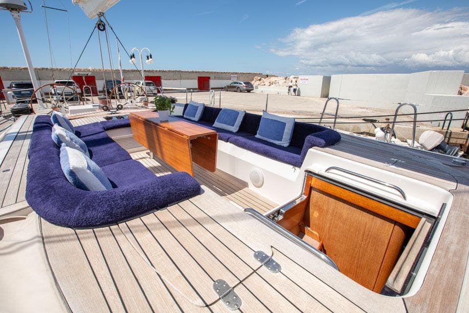 Luxurious 2001 Nautor Swan 80 yacht deck with plush seating and wooden table.