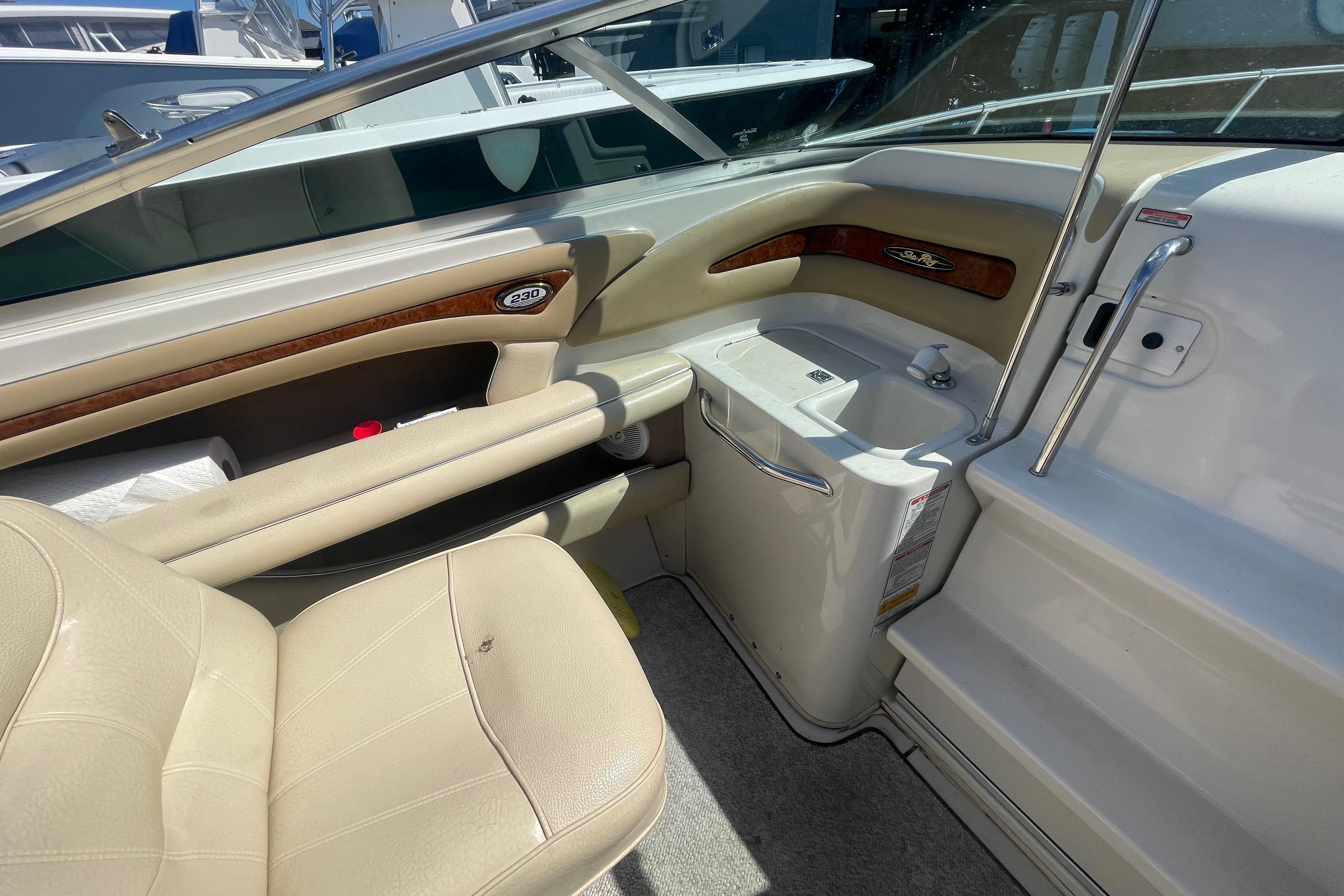 Interior of a 2000 Sea Ray 230 Signature boat, featuring beige seating and wood accents.
