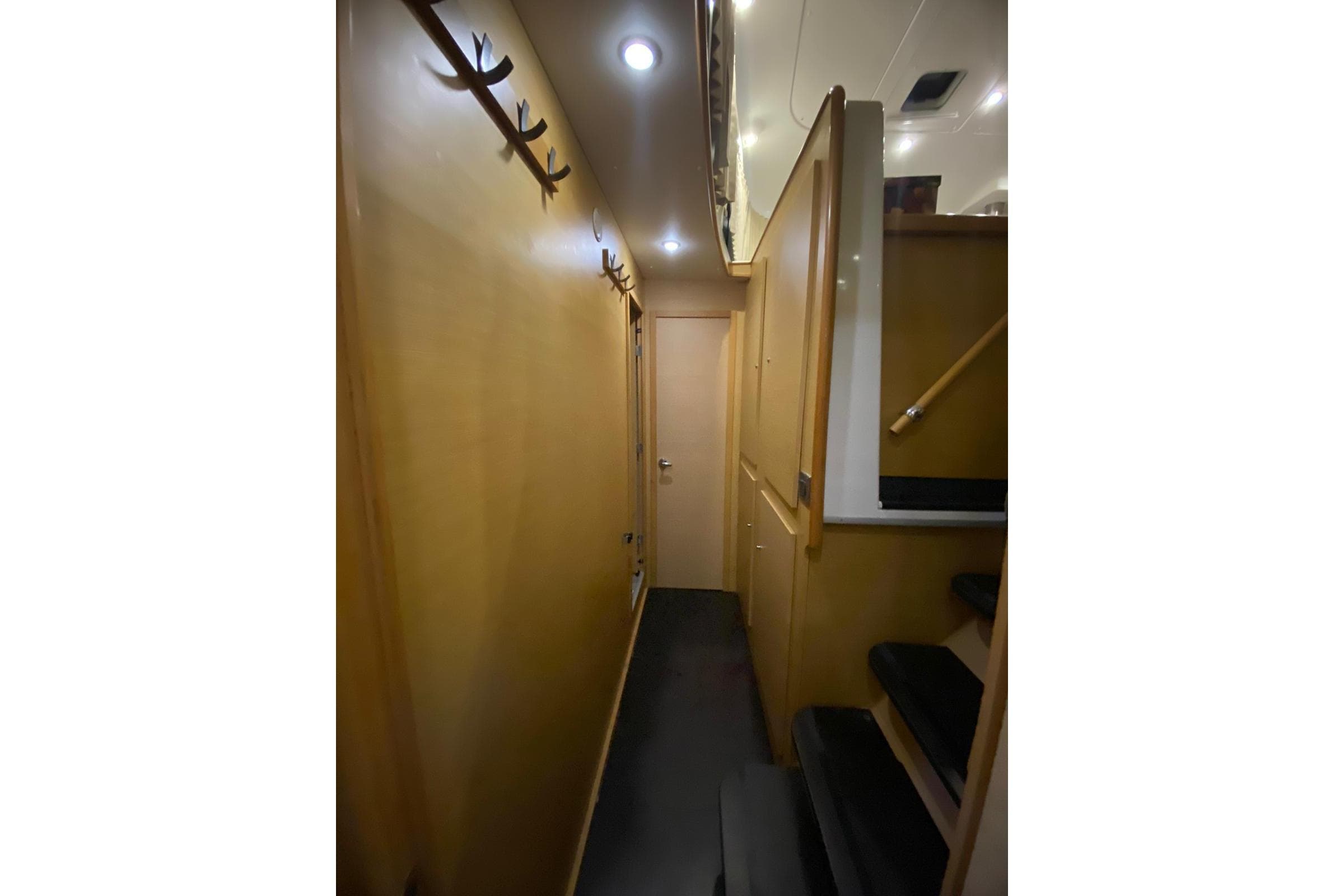 Narrow hallway inside 2008 Lagoon 440 yacht, featuring wooden walls and ceiling lights.