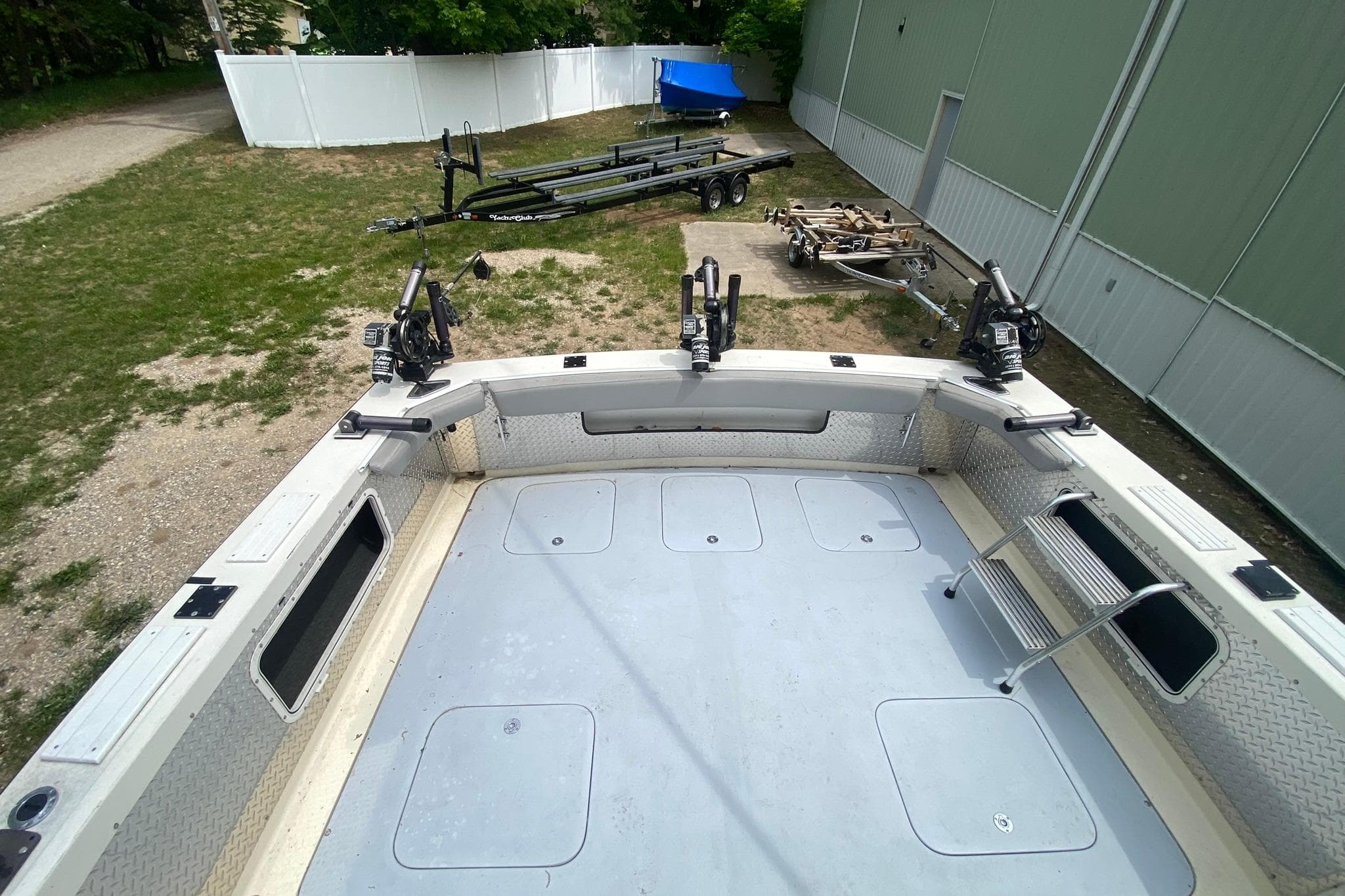 1977 Bertram 28 Flybridge boat deck with fishing rod holders and trailers in the background.