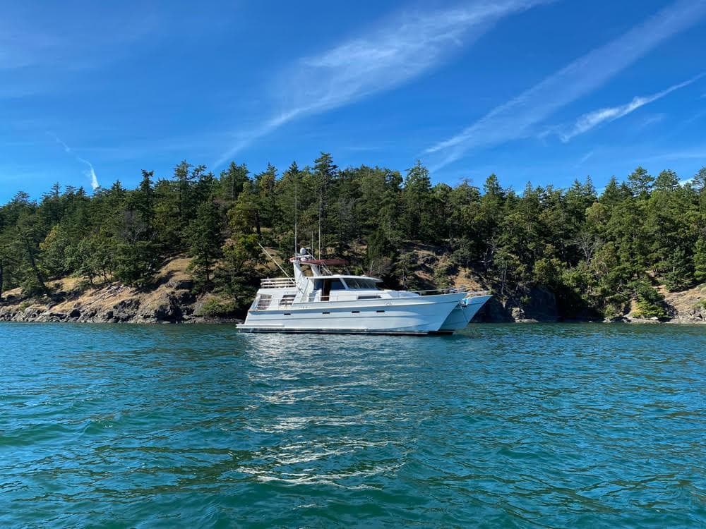 2001 Malcolm Tennant Pachoud Pilothouse Powercat on scenic waterway with forested shoreline.